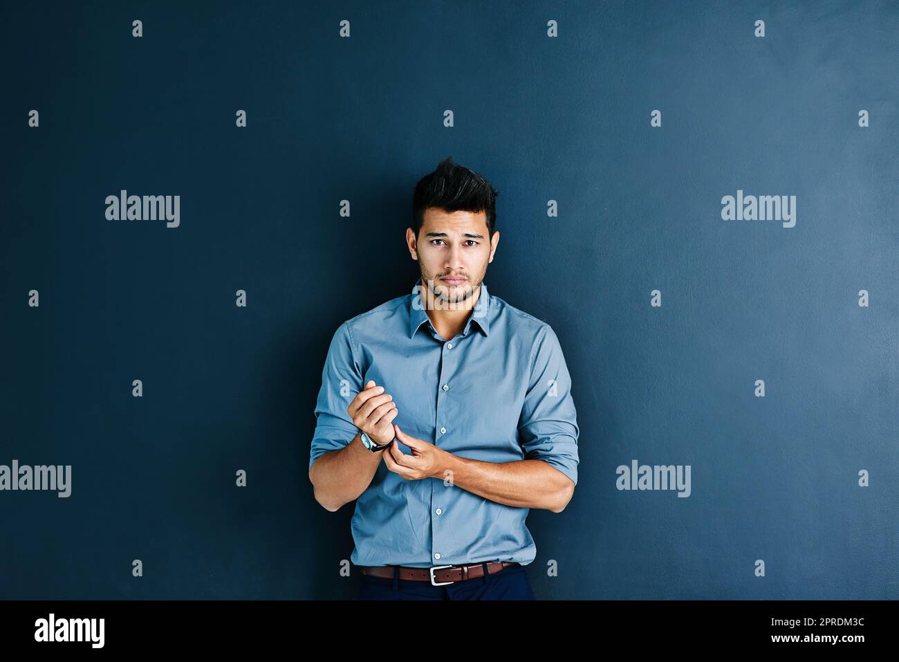 Es liegt ein weiter Weg vor uns, aber ich bin bereit. Studioporträt eines gutaussehenden jungen Geschäftsmannes, der seine Armbanduhr vor einem grauen Hintergrund anpasst. Stockfoto