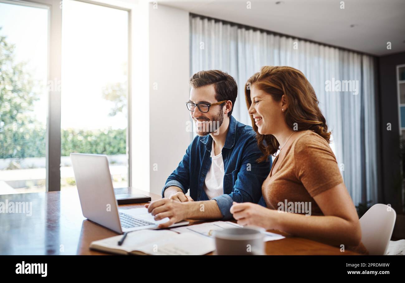 Wir finden immer gute Tipps zum Sparen online. Ein junges Paar, das sich online Videos ansieht, während es zu Hause sein monatliches Budget macht. Stockfoto