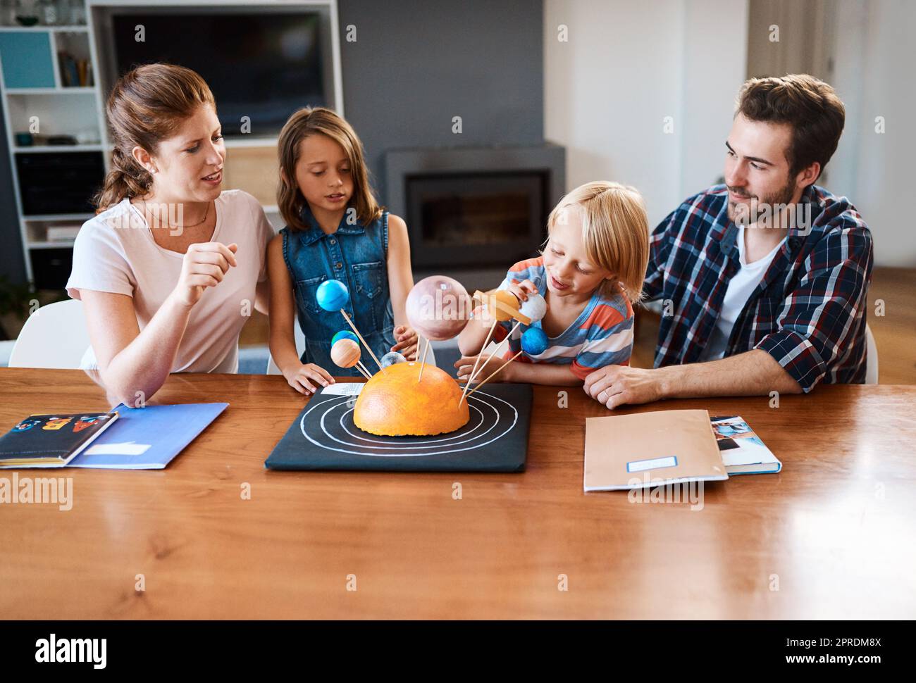 HES plant, eines Tages zum Mond zu reisen. Eine schöne junge Familie arbeitet zusammen an einem wissenschaftlichen Projekt zu Hause. Stockfoto