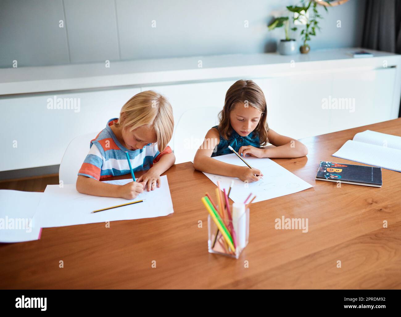 Sie werden eines Tages die Geschichte neu schreiben. Zwei entzückende kleine Kinder machen ihre Hausaufgaben zusammen zu Hause. Stockfoto