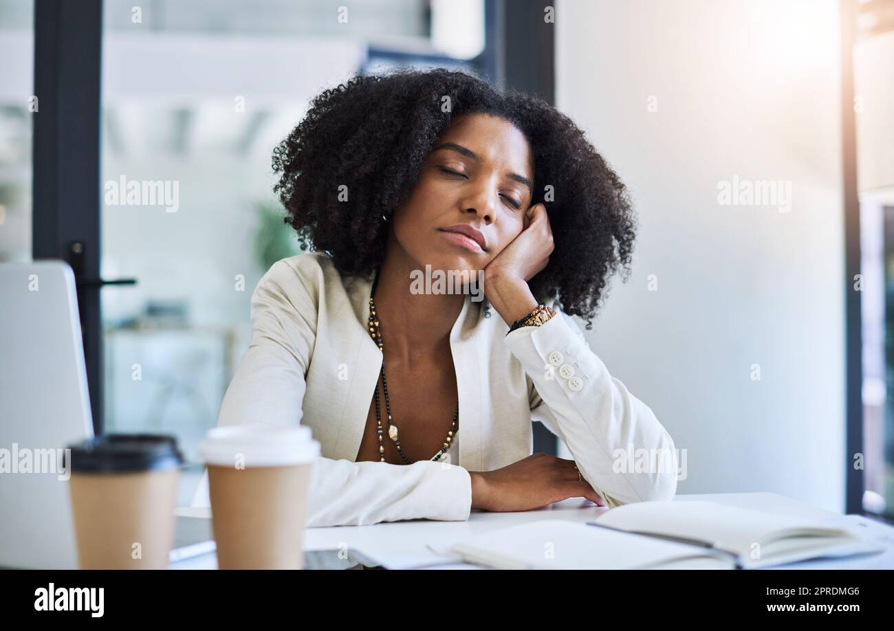 Ein kurzes Nickerchen, um mich ein wenig zu erfrischen. Eine junge Geschäftsfrau, die an ihrem Schreibtisch ein Nickerchen macht. Stockfoto