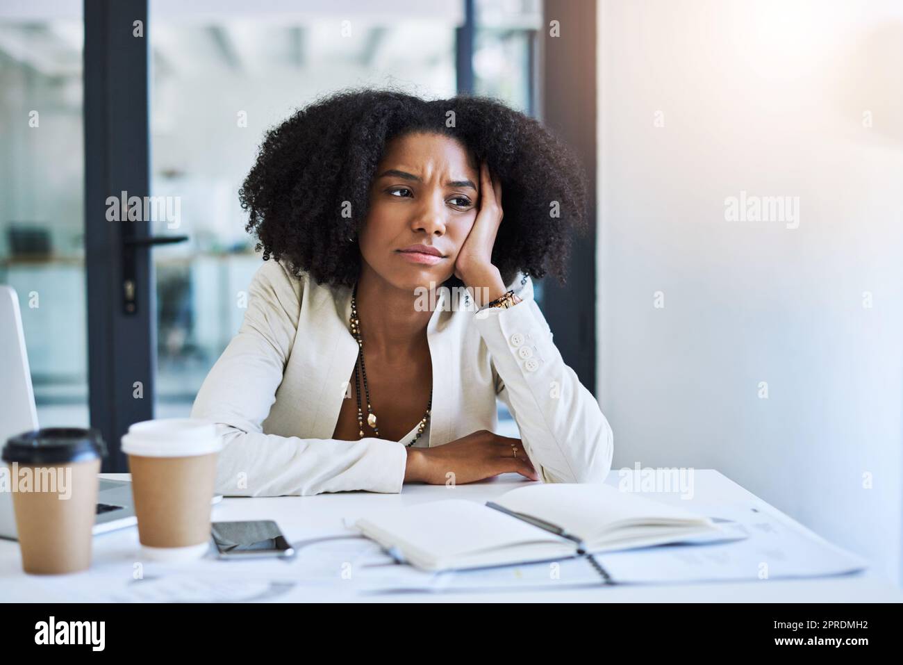 Dieses ganze Projekt verwirrt mich. Eine junge Geschäftsfrau, die gestresst und frustriert an ihrem Schreibtisch aussieht. Stockfoto