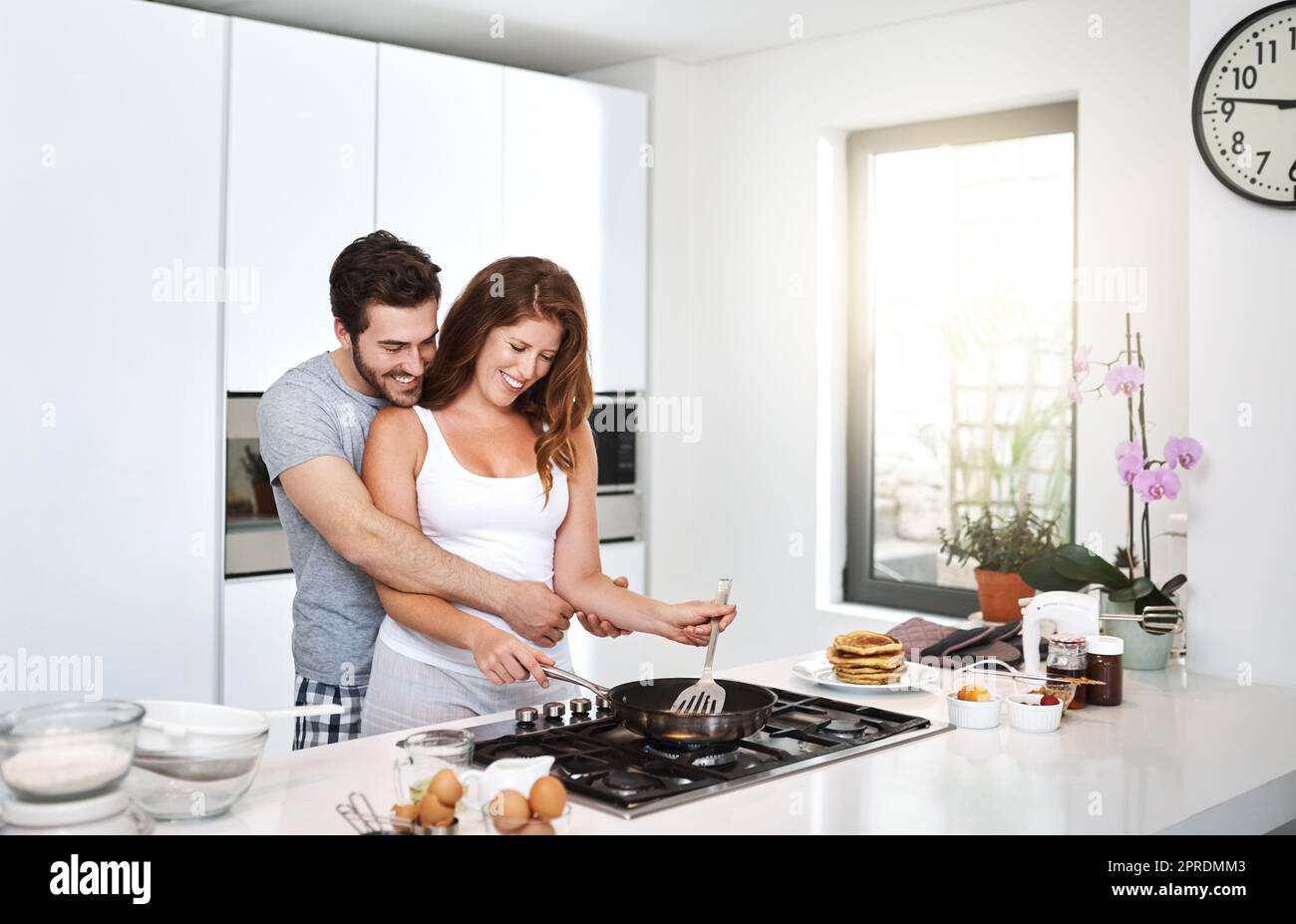 Wir könnten mehr Morgen wie diesen aushalten. Ein glückliches junges Paar, das morgens das Frühstück zubereitete. Stockfoto