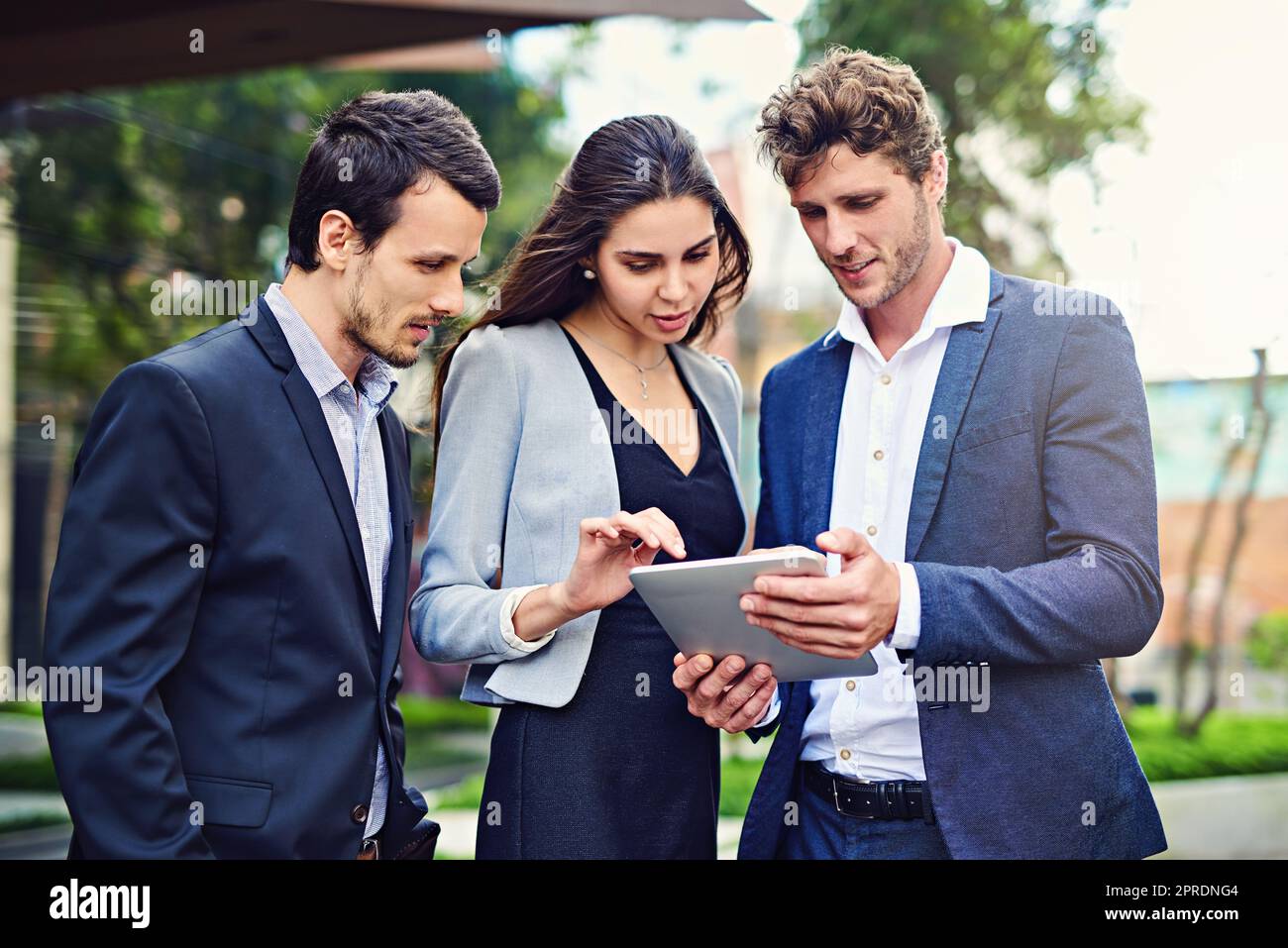 Sie arbeiten zusammen, um den Standort zu finden. Geschäftsleute benutzen draußen ein Tablet. Stockfoto