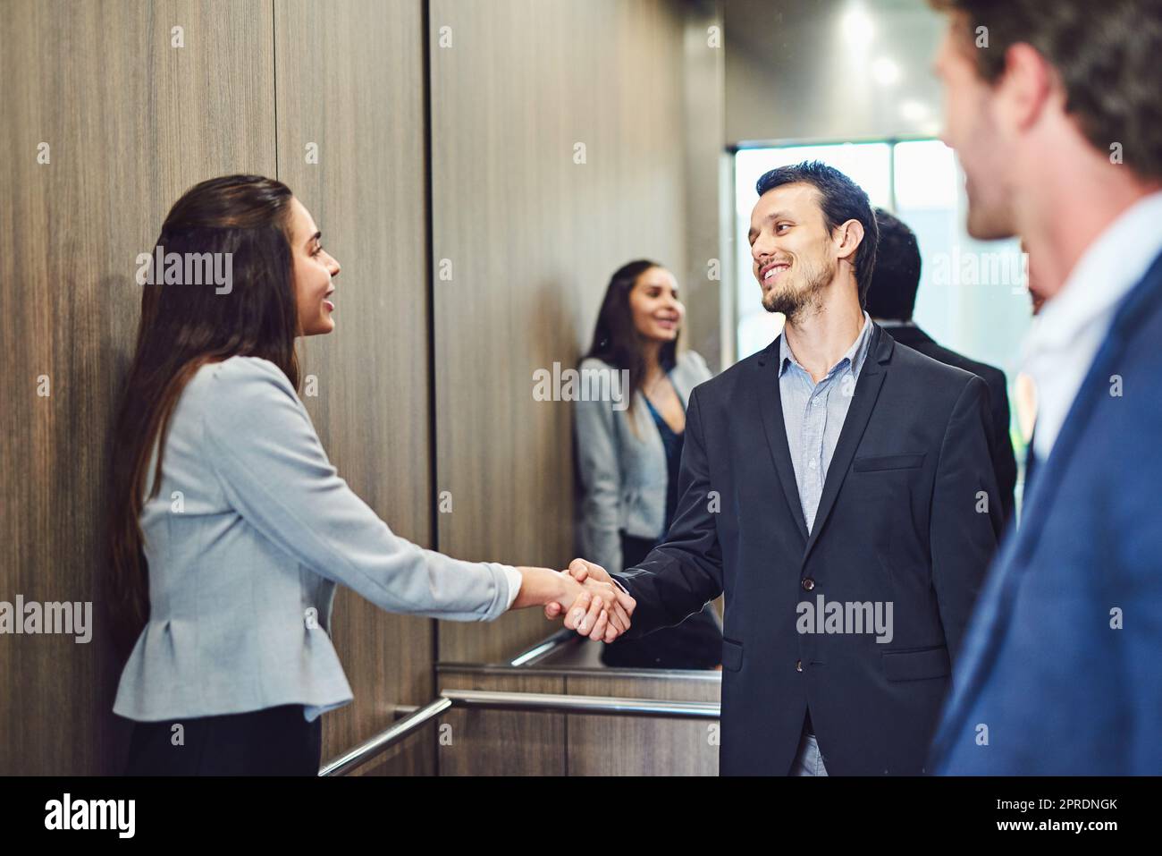 Sie kamen zur Konferenz, um Geschäftsleute zu treffen. Geschäftsleute trafen sich und begrüßten sie in einem Aufzug. Stockfoto