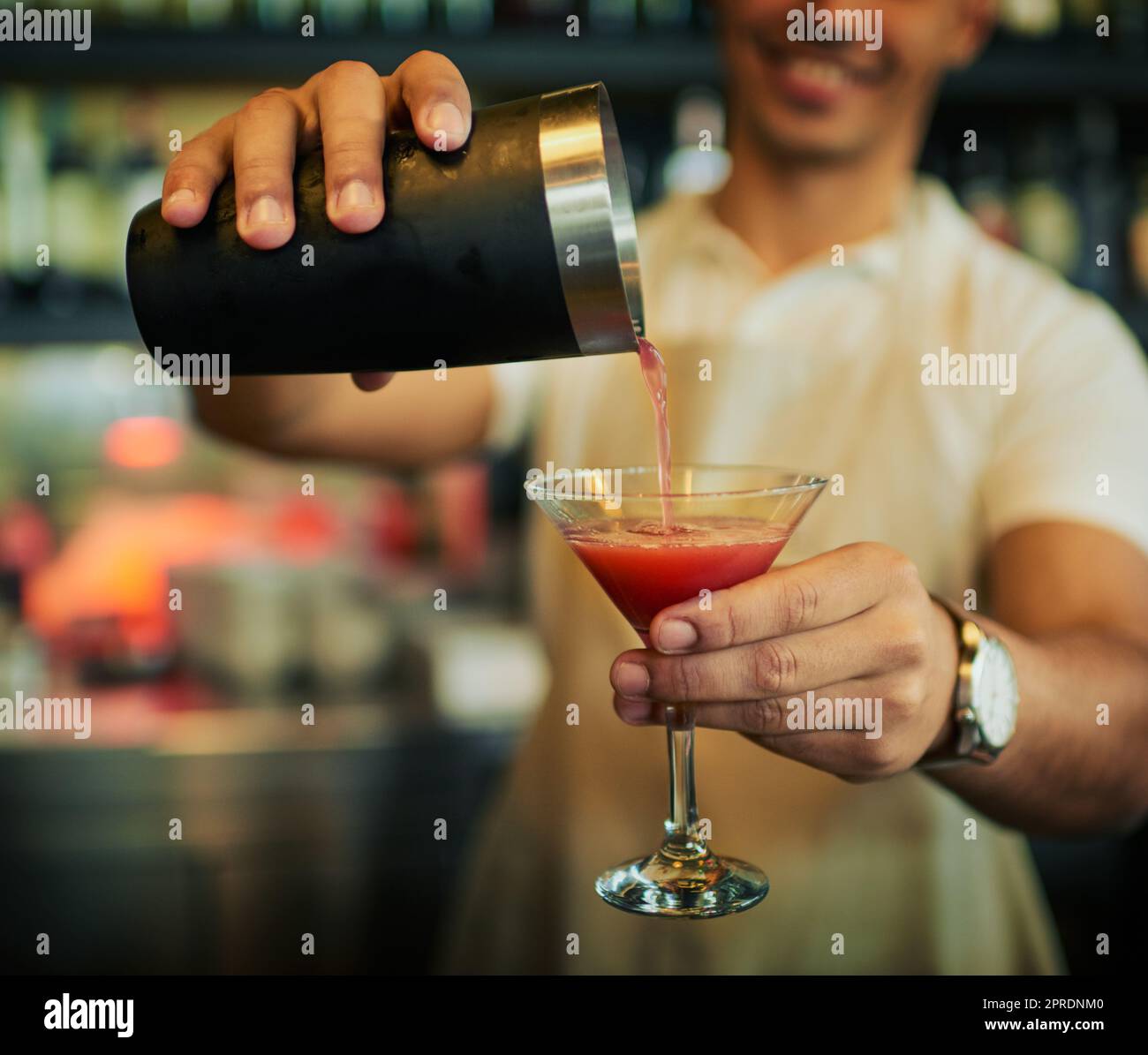 Ein nicht erkennbarer Barkeeper gießt tagsüber in einem schicken Glas in einem Restaurant ein Getränk. Stockfoto