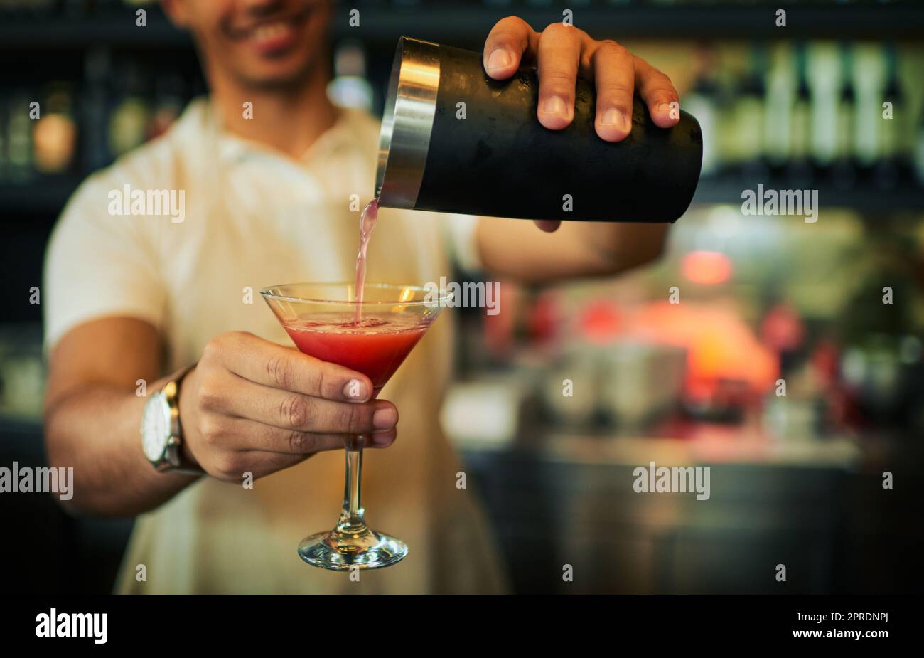 Ihr Können ist bekannt. Ein nicht erkennbarer Barkeeper, der tagsüber in einem schicken Glas in einem Restaurant ein Getränk ausgießt. Stockfoto