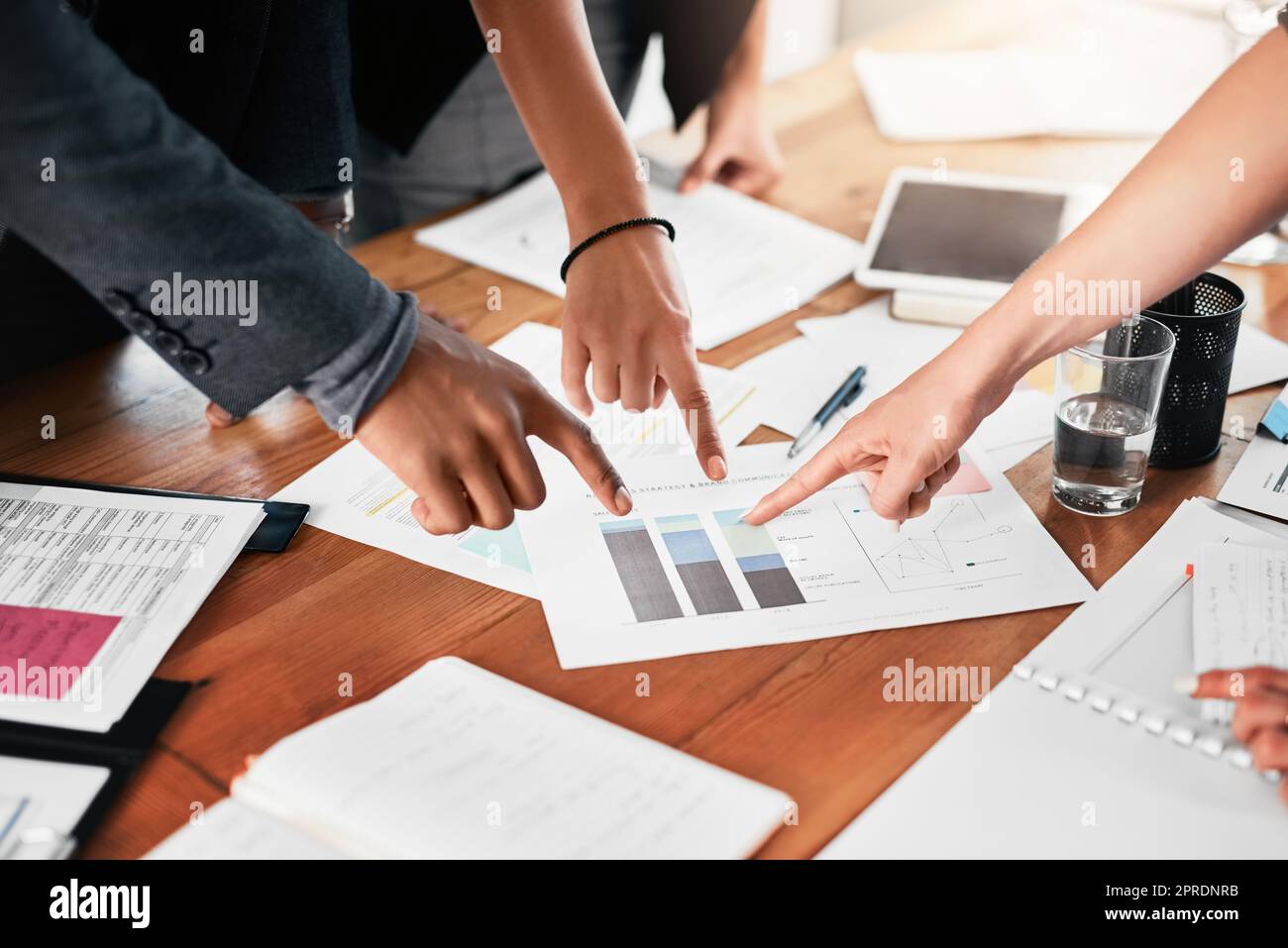 Den Fokus auf einen bestimmten Punkt zu richten. Nahaufnahme einer Gruppe von nicht erkennbaren Geschäftsleuten, die in einem Büro auf Papierkram zeigen. Stockfoto
