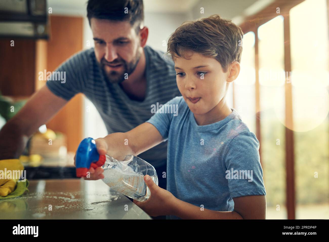 Nehmen Sie diese Keime. Ein Vater und Sohn reinigen die Küchentheke zusammen zu Hause. Stockfoto