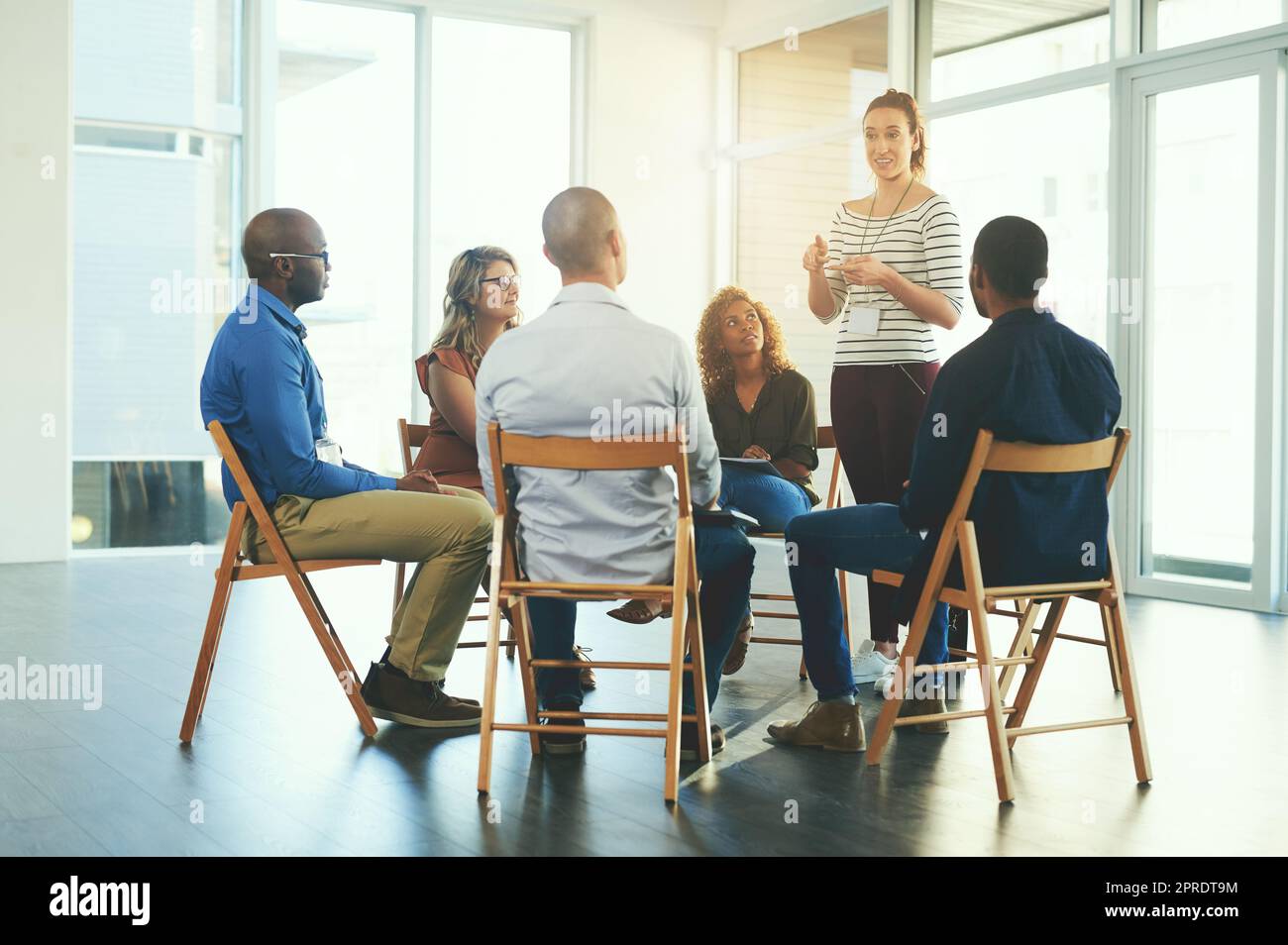 Weibliche Führungskraft oder CEO, die in einem Teammeeting über Teamentwicklung und Erfolg spricht. Gruppe von Marketingteams, die gemeinsam in einem Coaching- oder Schulungsseminar in einem Unternehmen über eine Arbeitsstrategie spricht Stockfoto