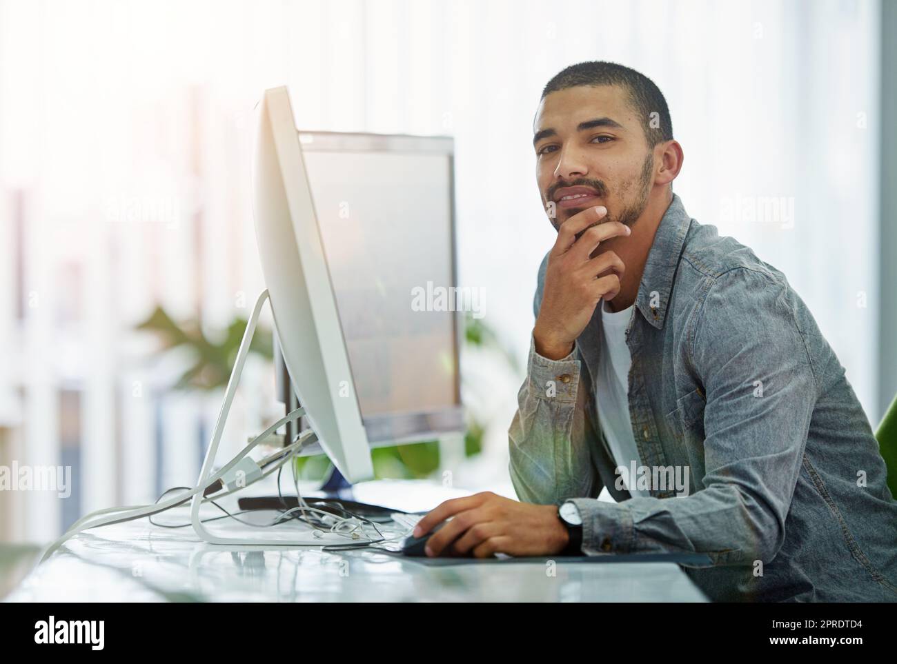 Trendiger Geschäftsmann, IT- oder Softwareingenieur mit guter Idee für Innovation und Webentwicklung im Technologieunternehmen. Porträt eines jungen ux- oder ui-Designers mit einem modernen Desktop-Computer Stockfoto