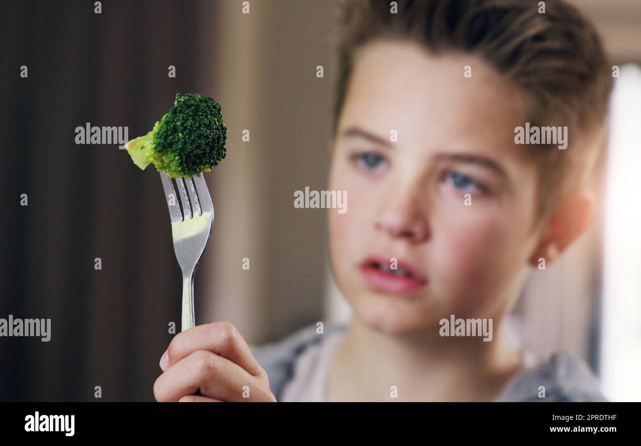 Ein kleiner Junge, der sich weigert, seinen Brokkoli zu Hause zu essen. Stockfoto
