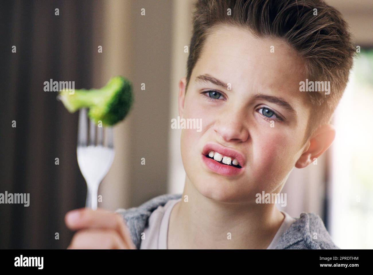 Ein kleiner Junge, der sich weigert, zu Hause seinen Brokkoli zu essen. Stockfoto