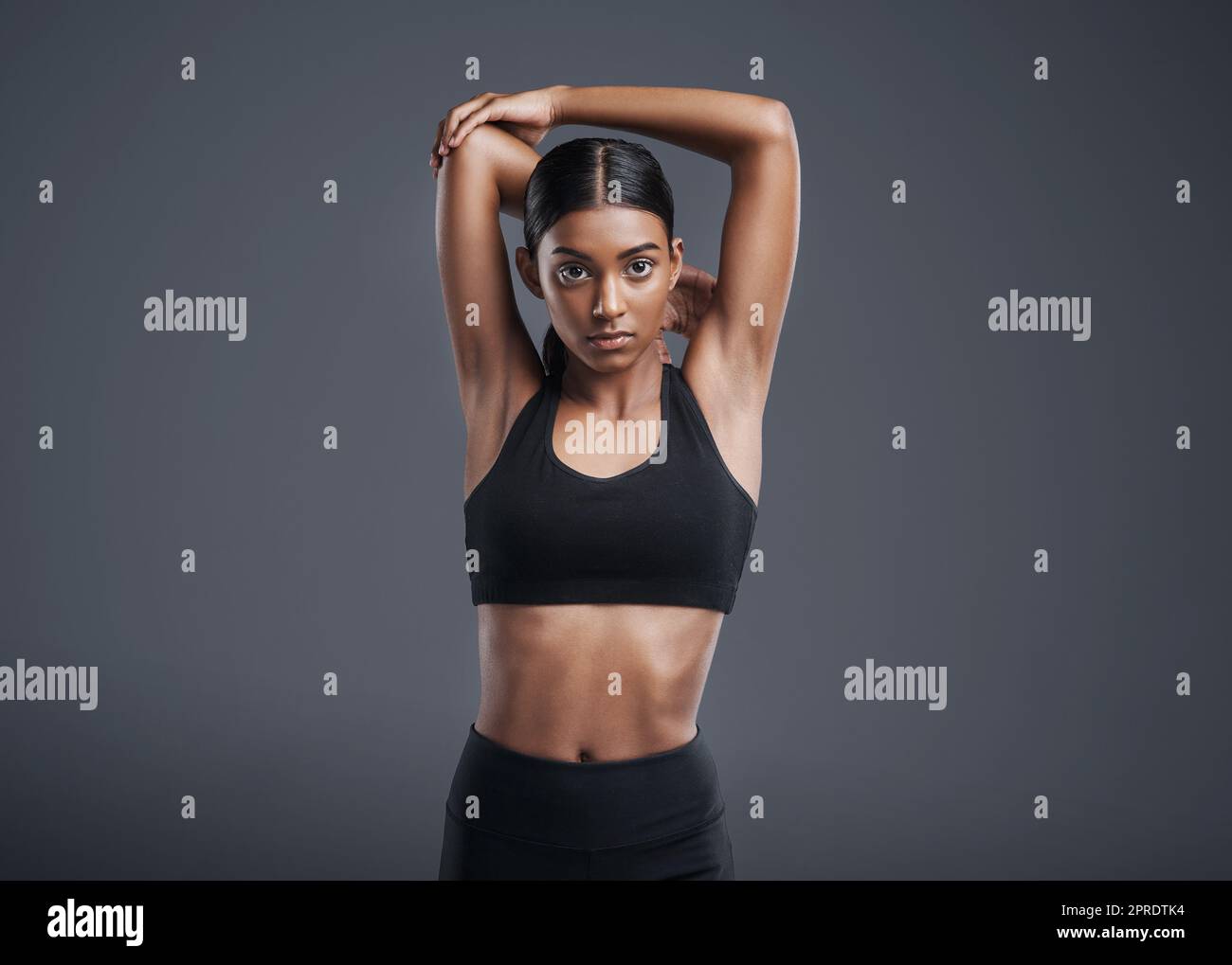 Bleiben Sie diszipliniert und Sie werden Ergebnisse sehen. Studioportrait einer sportlichen jungen Frau, die ihre Arme vor einem grauen Hintergrund ausstreckt. Stockfoto
