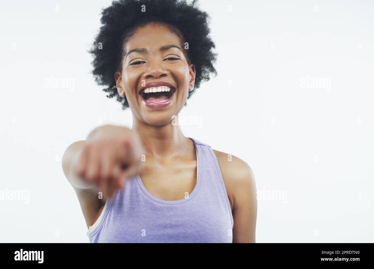 Lachend laut. Studioaufnahme einer attraktiven jungen Frau, die vor grauem Hintergrund mit dem Finger auf die Kamera zeigt. Stockfoto