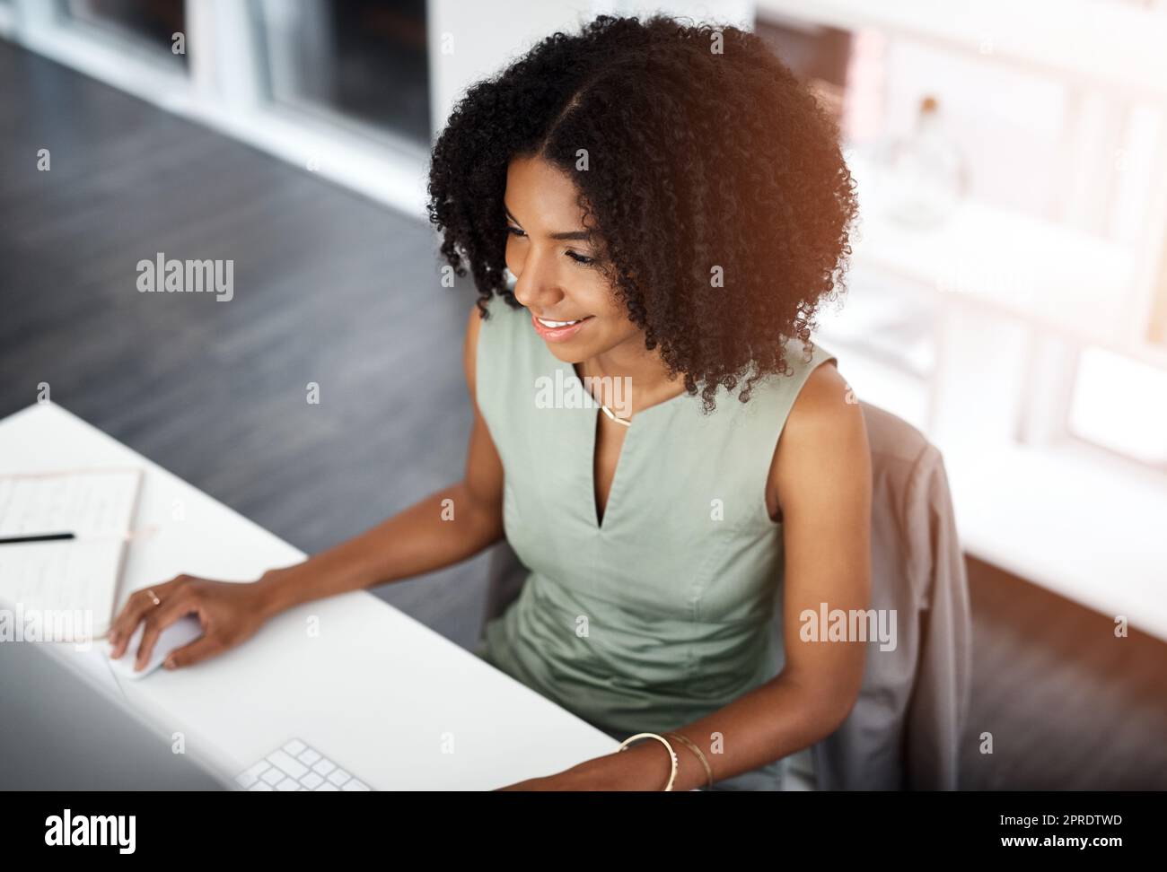 Ihre Arbeit ist immer auf dem neuesten Stand. Eine junge Geschäftsfrau, die an ihrem Schreibtisch in einem modernen Büro arbeitet. Stockfoto