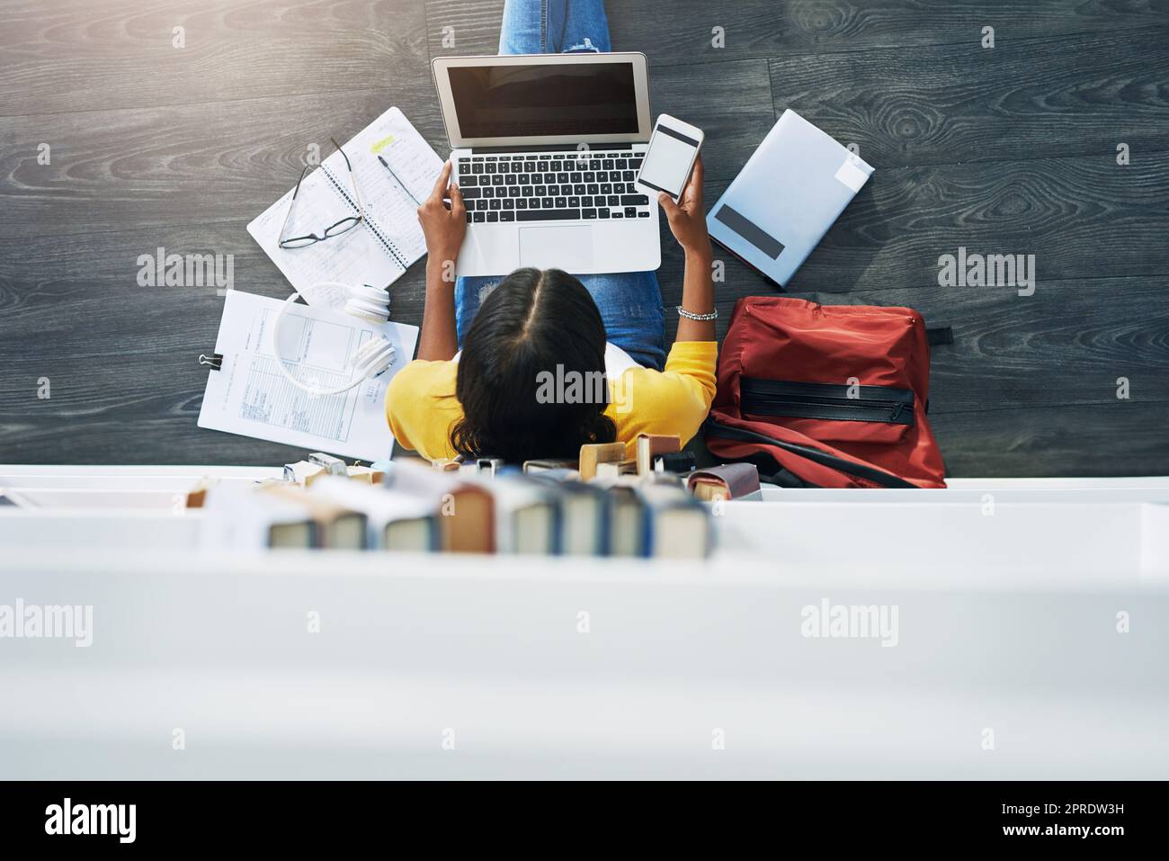 Forschung von mehreren Geräten aus. High-Angle-Aufnahme einer jungen Studentin, die zu Hause studiert. Stockfoto