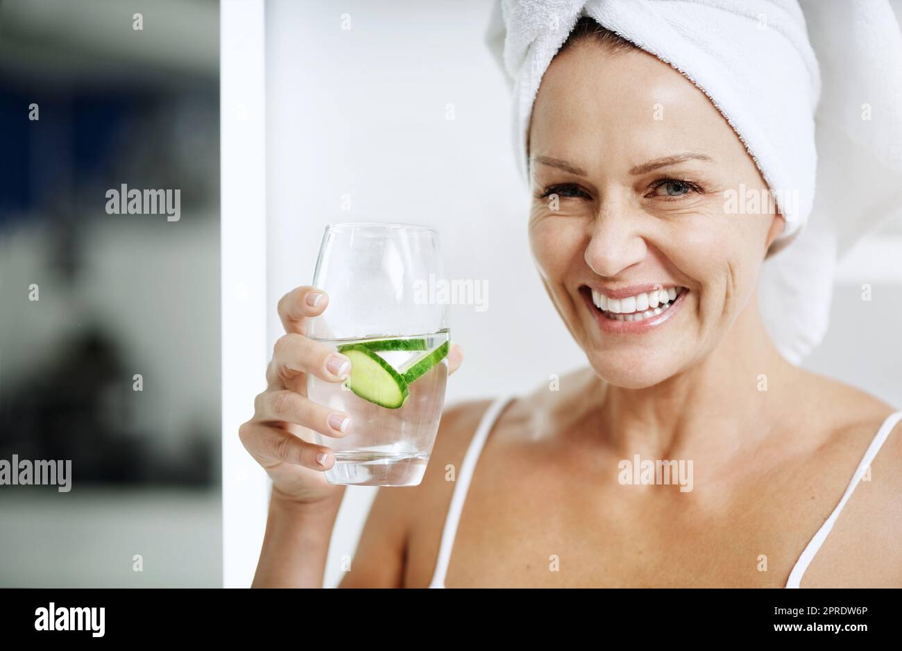 Es ist, was für mich funktioniert. Eine reife Frau hält ein Glas Wasser mit Gurke in. Stockfoto