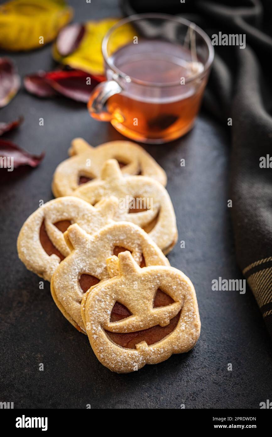 Linzer Kekse in Form eines Halloween Kürbisses auf dem schwarzen Tisch. Stockfoto