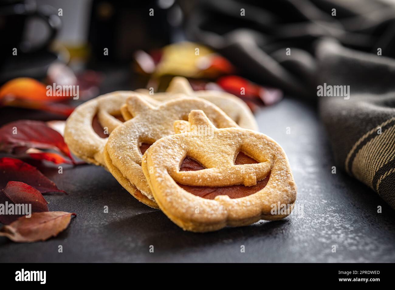 Linzer Kekse in Form eines Halloween Kürbisses auf dem schwarzen Tisch. Stockfoto