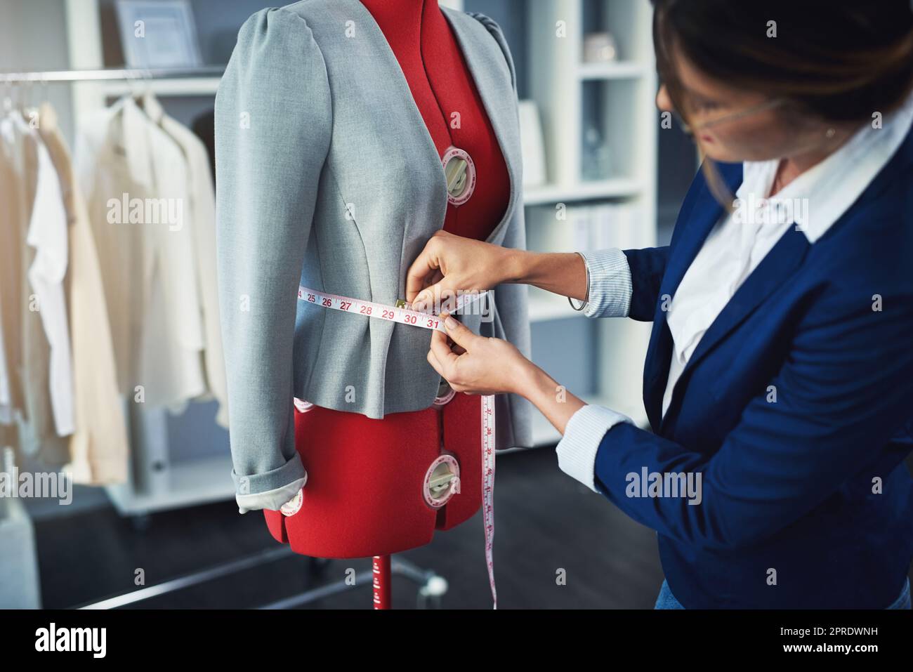 Eine attraktive junge Modedesignerin, die in ihrem Designstudio an einer Schaufensterpuppe arbeitet. Stockfoto