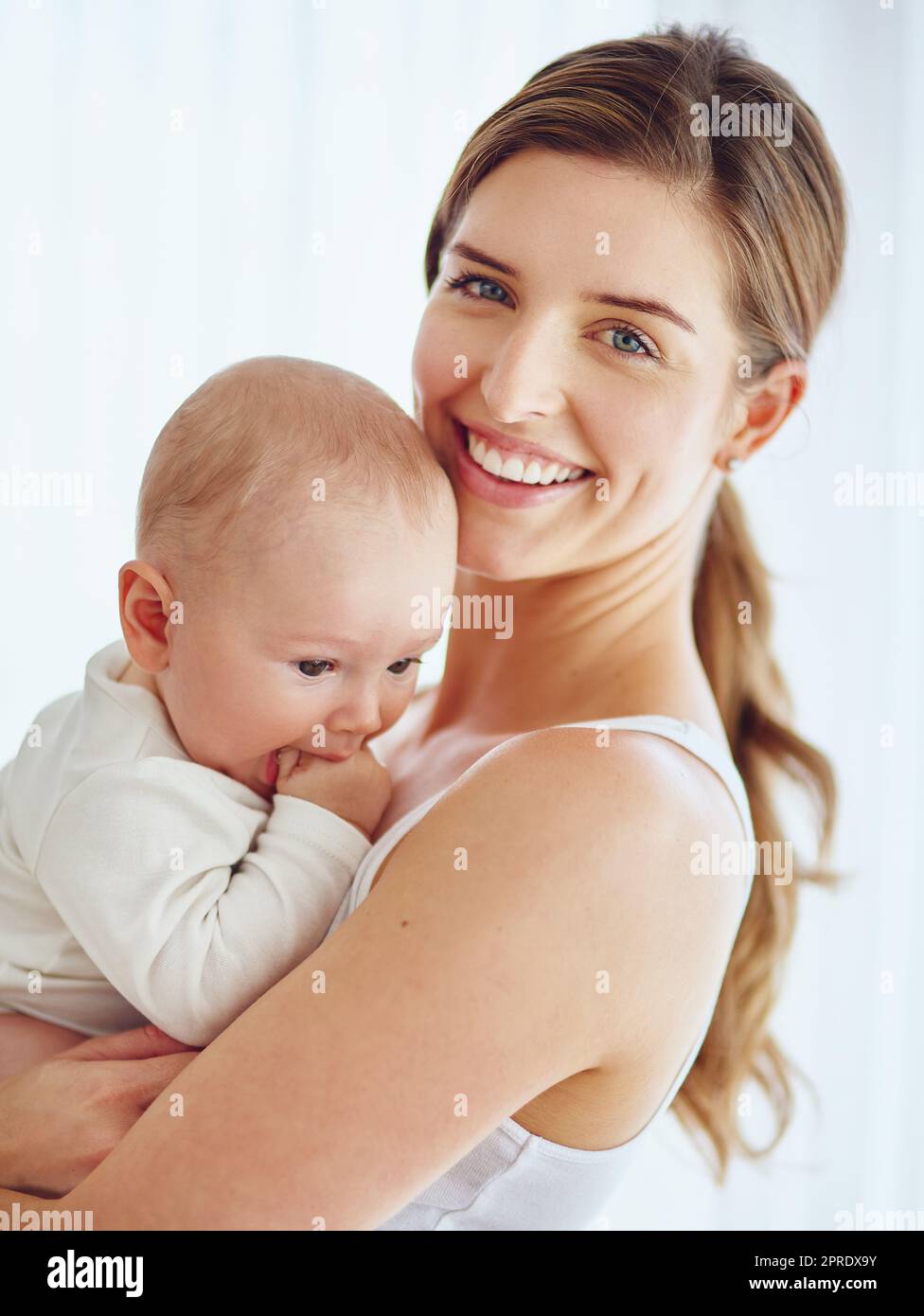 Mutter, die sich mit dem kleinen Jungen verbindet, lächelt und die Zeit mit der Familie in einem Zimmer zu Hause genießt. Porträt eines glücklichen, liebevollen und fürsorglichen alleinerziehenden Elternteils, der ein bezauberndes, süßes und kleines Neugeborenes in der Hand hält oder trägt Stockfoto