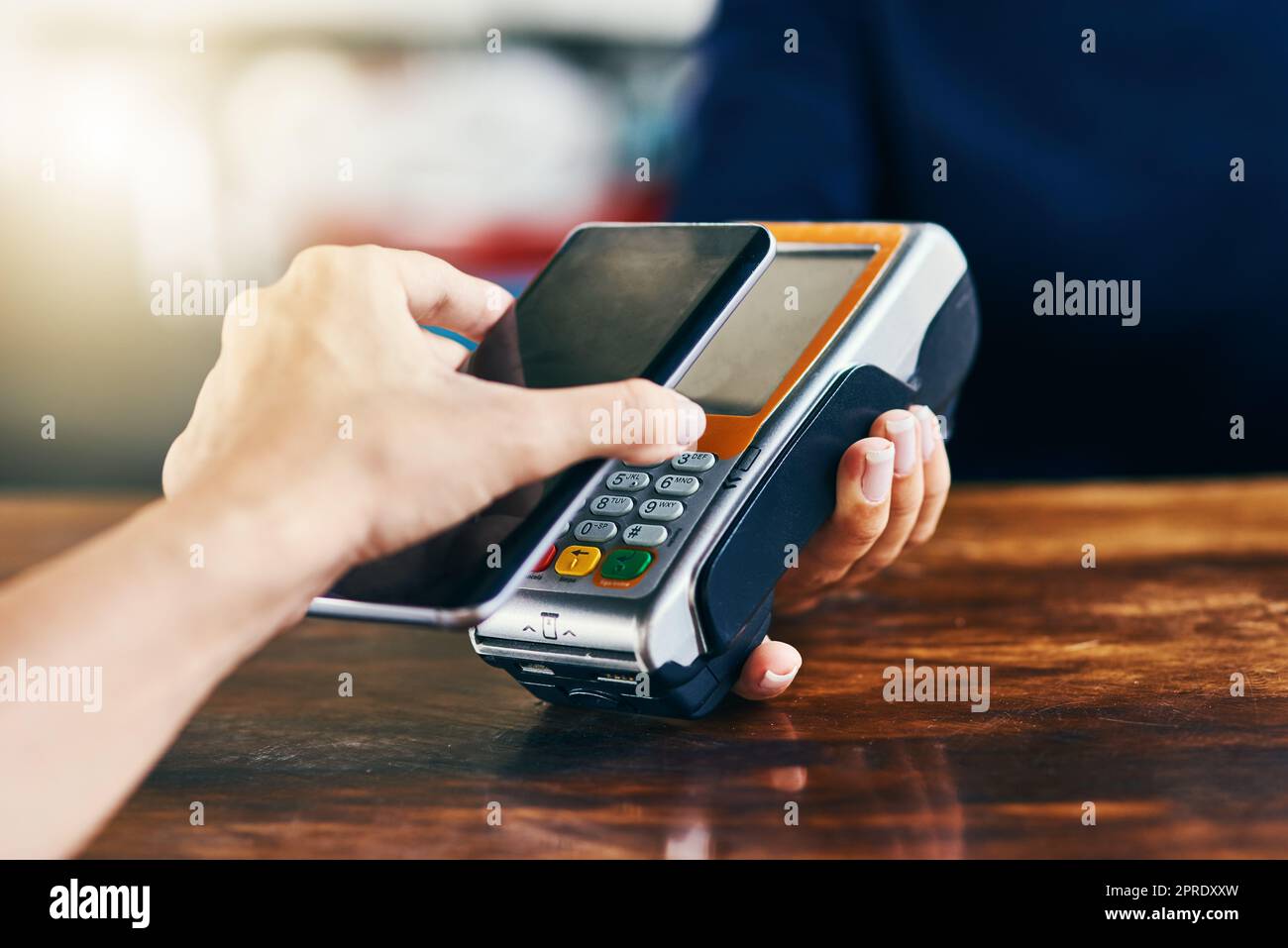 Es ist so einfach, wie Ihr Telefon herauszunehmen. Nahaufnahme einer nicht wiedererkennbaren Person, die tagsüber mit ihrem Handy eine Rechnung an einem Kartenautomaten in einem Café scannt und bezahlt. Stockfoto