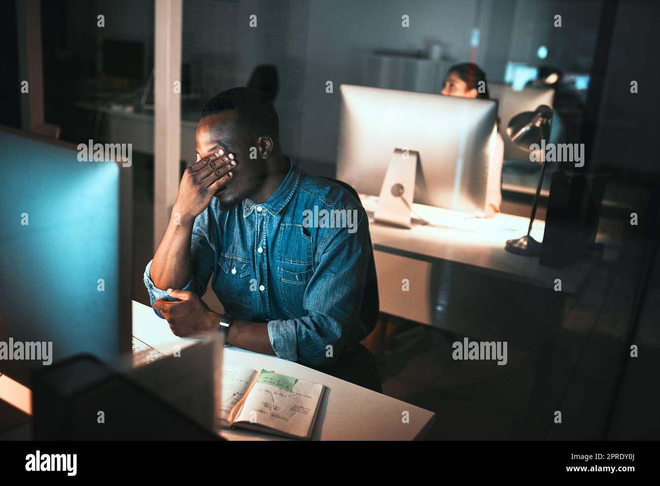 HES fühlt die Belastung. High-Angle-Aufnahme eines jungen männlichen Designers, der während der Arbeit am Computer im Büro gestresst aussieht. Stockfoto