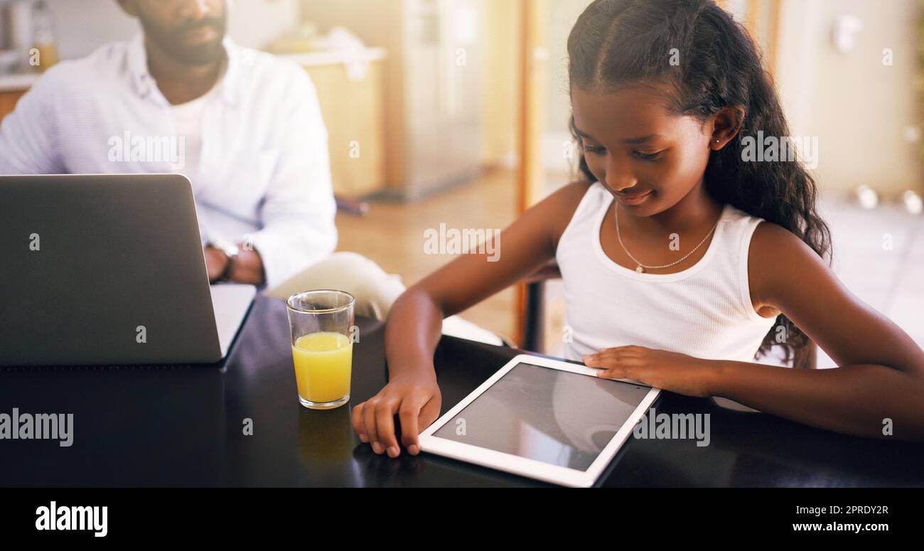 Digitale Bildung. Ein junger Vater und seine entzückende Tochter benutzen zu Hause ein Tablet. Stockfoto