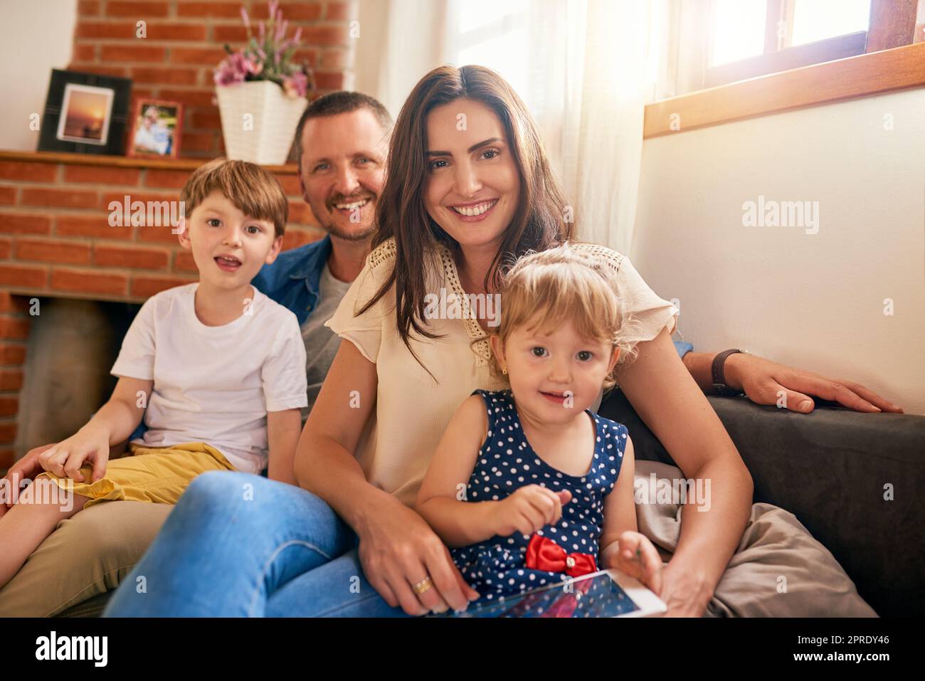 Nichts kann die Familienzeit ersetzen. Porträt einer glücklichen, jungen vierköpfigen Familie, die sich zu Hause auf dem Sofa entspannt. Stockfoto