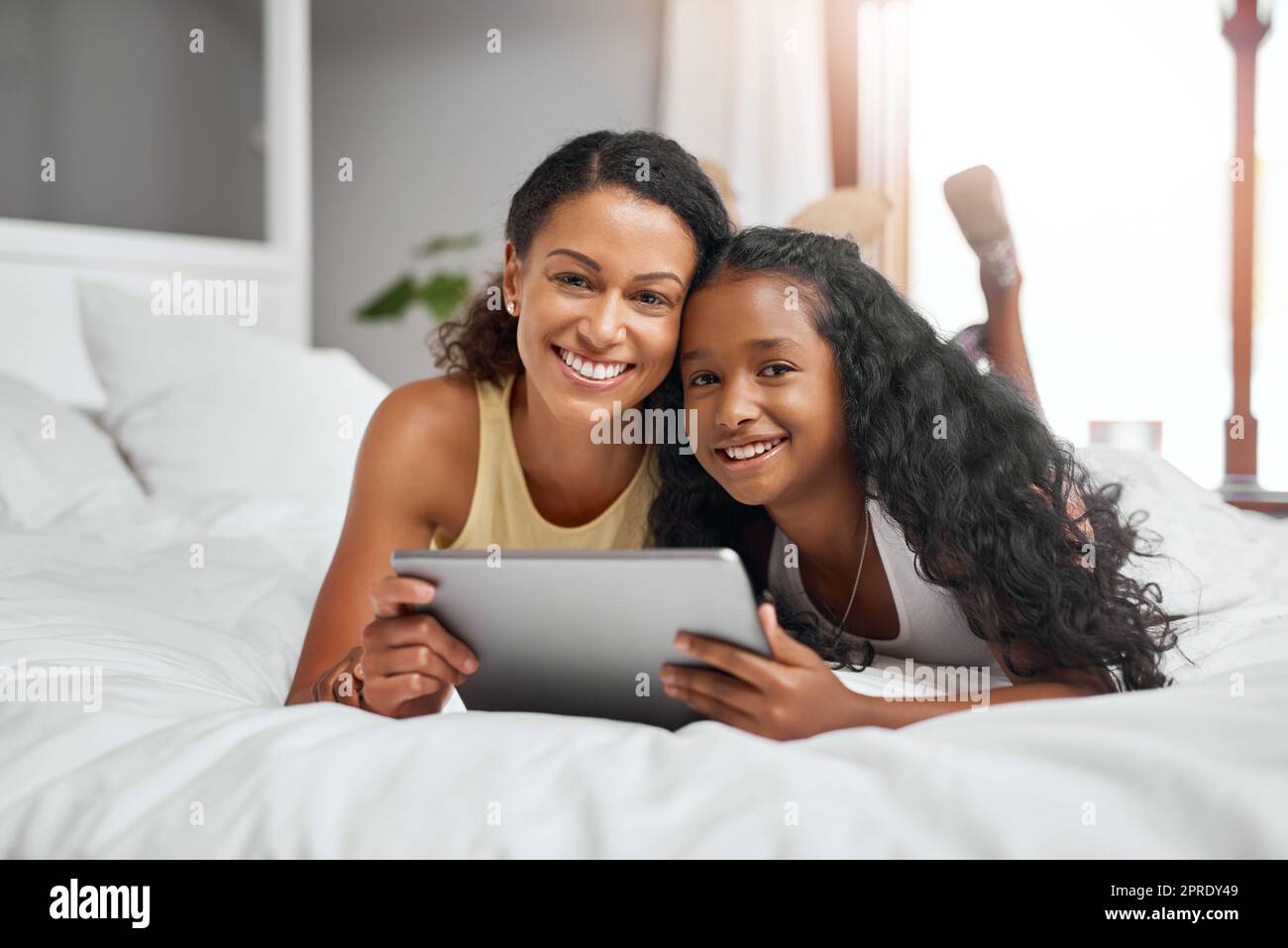 Eine Mutter und Tochter, die mit einem digitalen Tablet auf dem Bett lagen, haben sich immer über das Internet unterhalten. Stockfoto