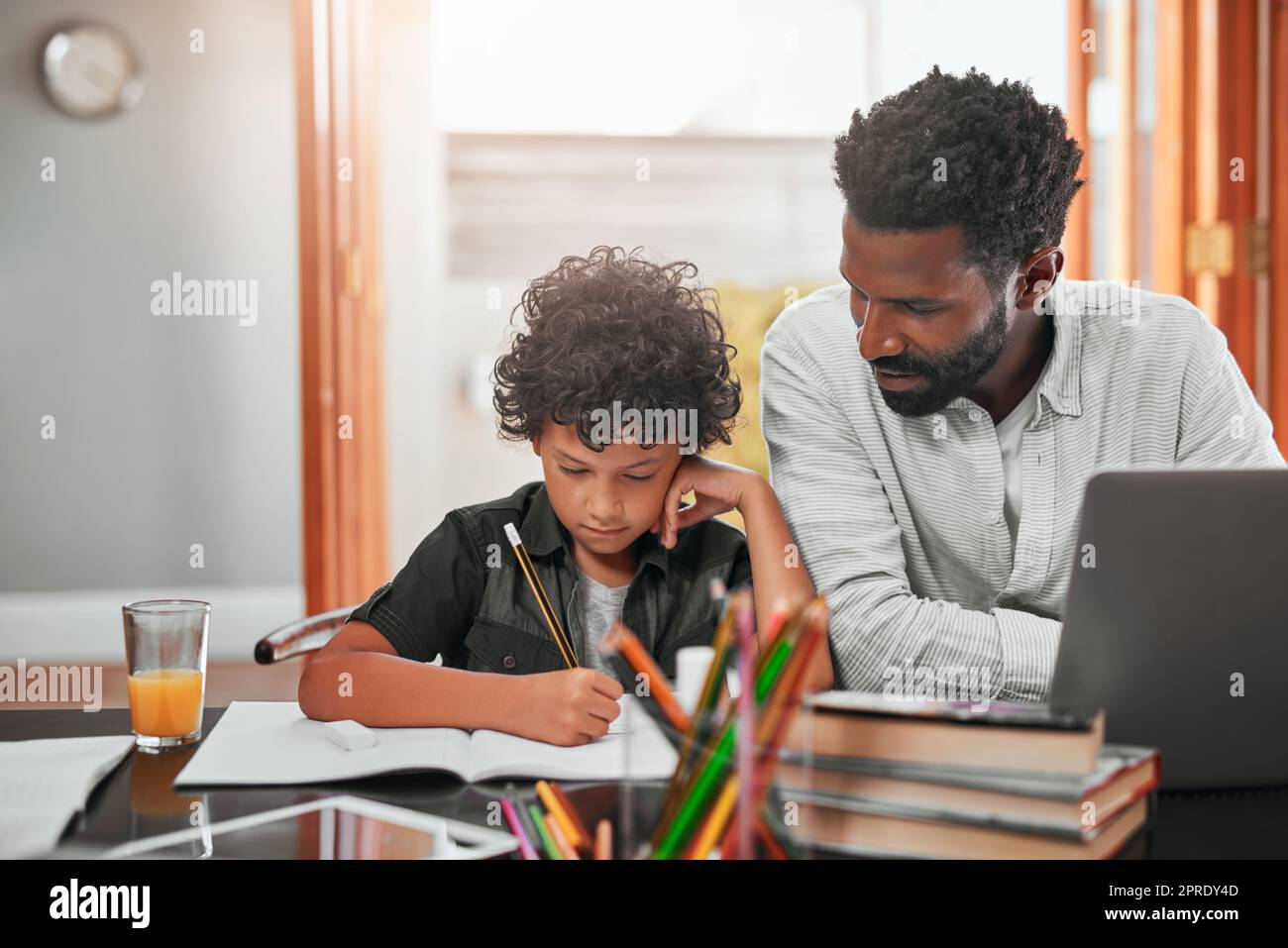 Finden Sie die Zeit, um Ihre Kinder zu unterstützen und zu ermutigen. Ein Mann hilft seinem Sohn bei seinen Hausaufgaben. Stockfoto
