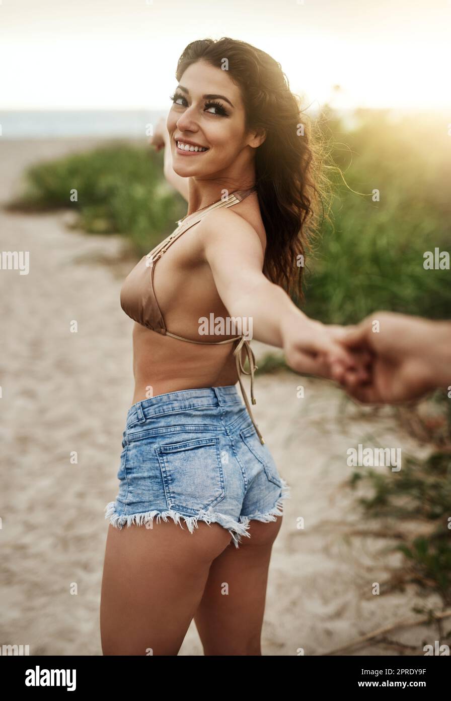 Ich hab dich Baby. Eine schöne junge Frau, die ihren Freund an der Hand am Strand führt. Stockfoto