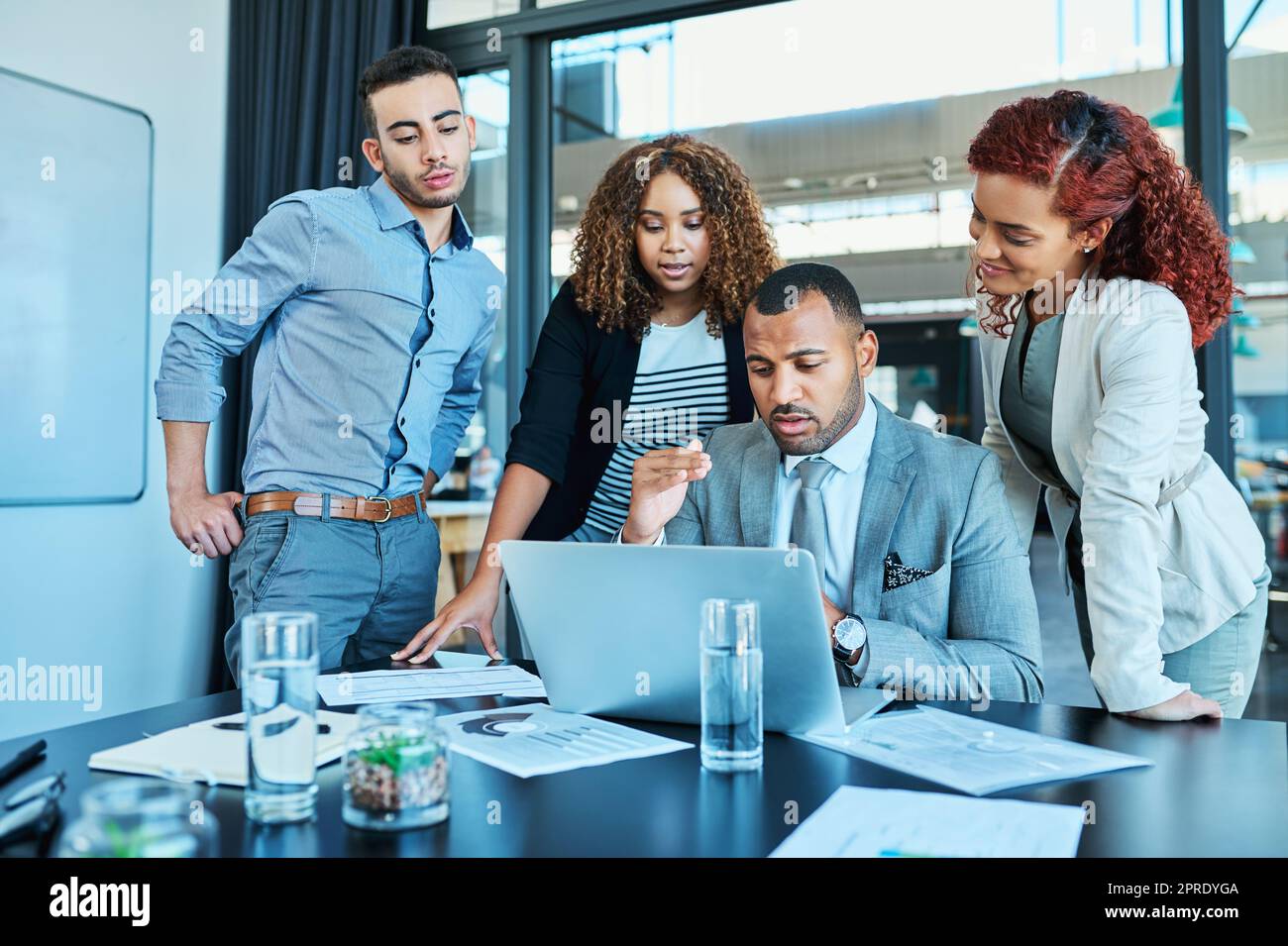 Es gibt keine Herausforderung, die sie gemeinsam besiegen können: Eine Gruppe von Geschäftsleuten, die in einem Büro an einem Laptop arbeiten. Stockfoto