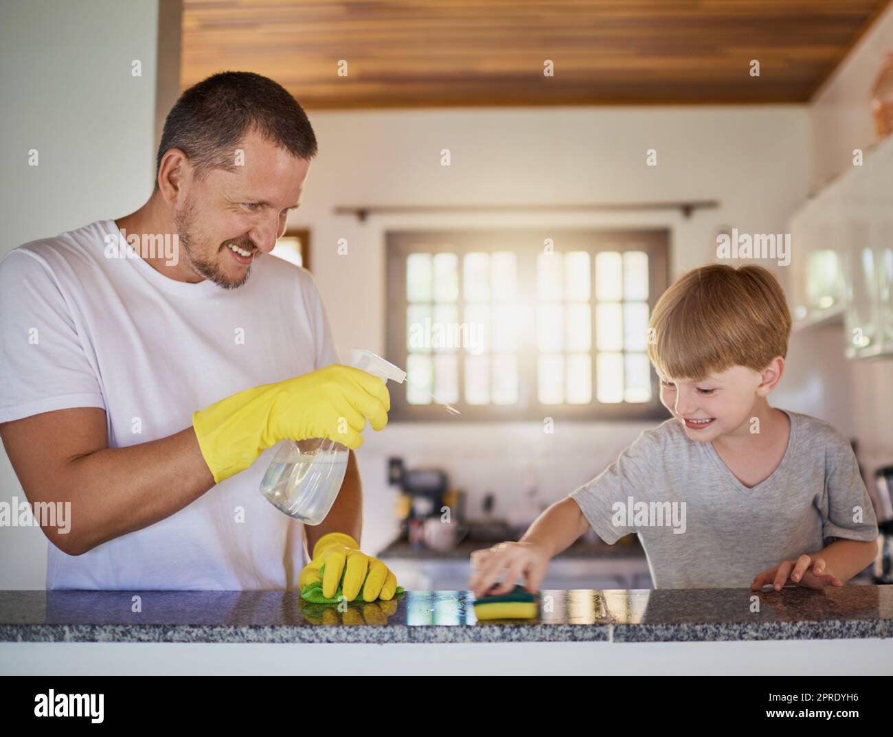 Der Unterricht für die Verantwortung von Kindern beginnt schon in jungen Jahren. Ein Vater und sein kleiner Sohn erledigen gemeinsam zu Hause Aufgaben. Stockfoto
