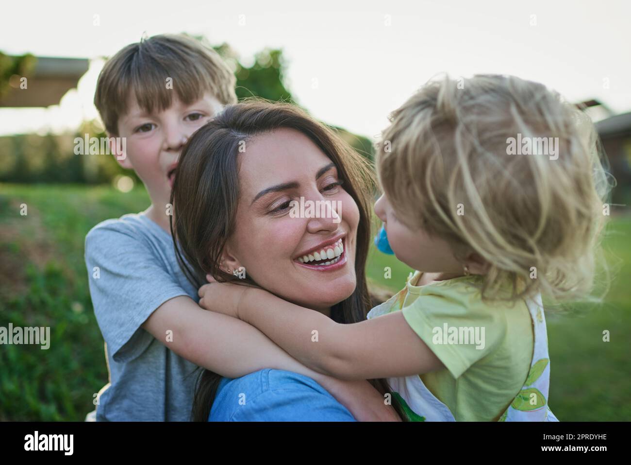Mama liebt dich auch. Eine Mutter, die sich mit ihren zwei kleinen Kindern im Freien verklebt. Stockfoto