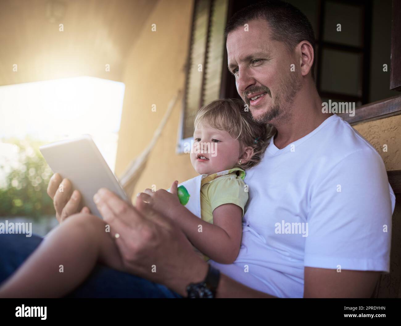 Ein Vater und seine kleine Tochter nutzen gemeinsam ein digitales Tablet im Freien. Stockfoto