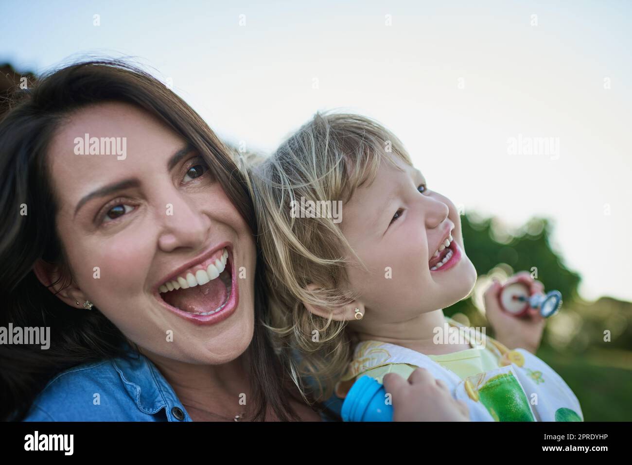 Eine Mutter und ihre kleine Tochter blasen im Freien. Stockfoto