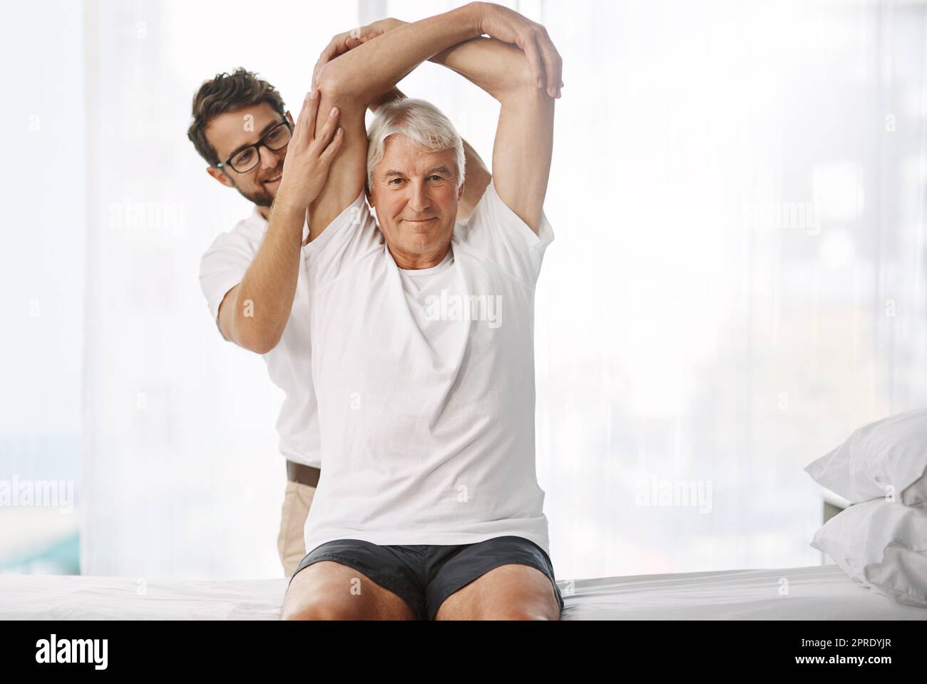 Lassen Sie mich wissen, wenn Sie Beschwerden haben. Ein junger männlicher Physiotherapeut, der mit einem älteren männlichen Patienten arbeitet. Stockfoto