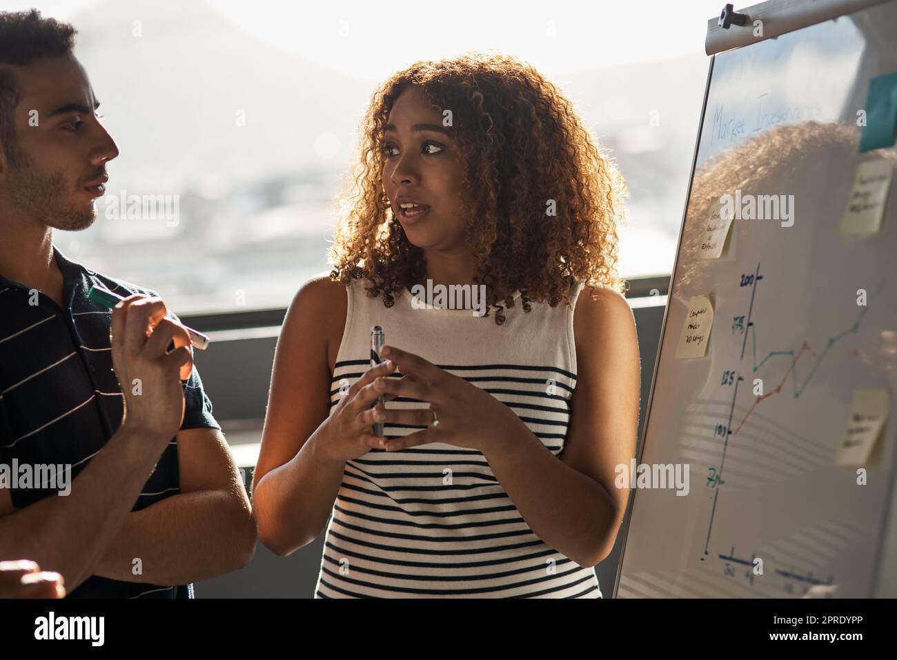 Diese Aufgabe erfordert unsere Fähigkeiten kombiniert. Zwei junge Designer Brainstorming auf einem Whiteboard in einem Büro. Stockfoto