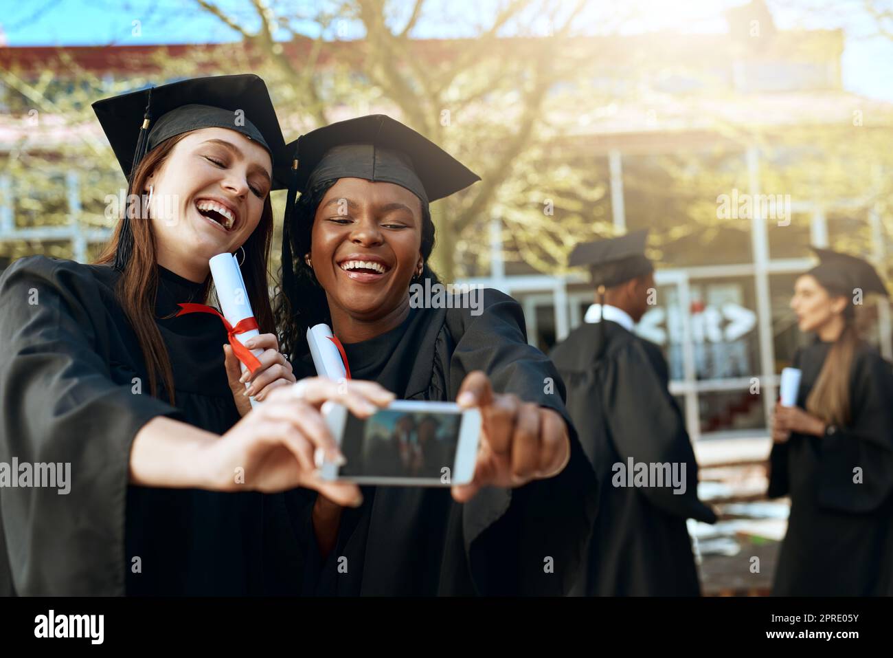 Unsere Träume wurden wahr: Zwei junge Frauen, die am Tag der Abschlussfeier Selfies mit einem Mobiltelefon gemacht haben. Stockfoto