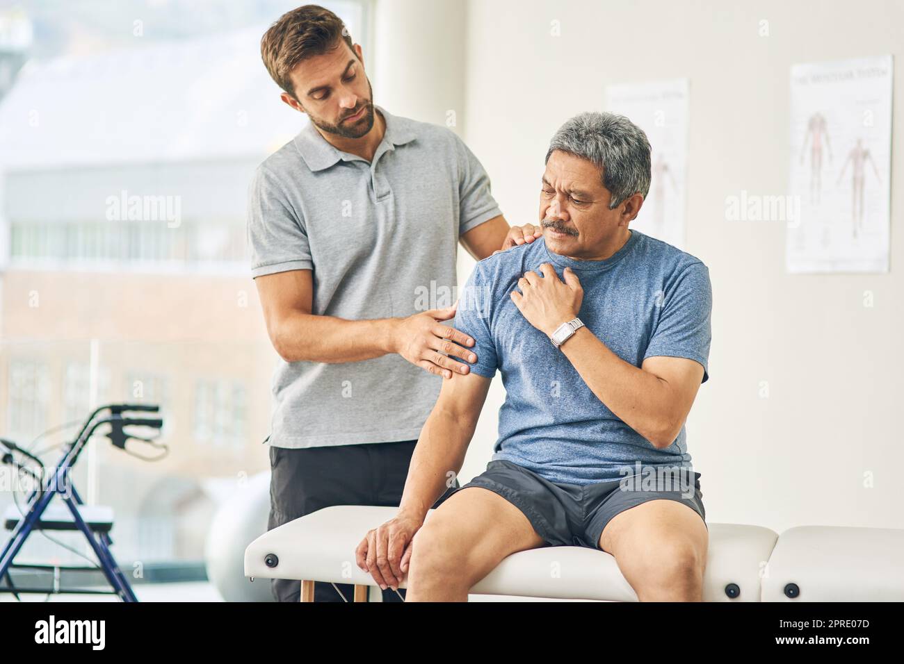 Wo tut es weh. Ein junger männlicher Physiotherapeut, der einem älteren Patienten bei der Genesung hilft. Stockfoto