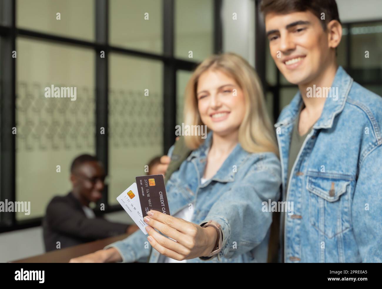 Ein fröhliches junges Paar checkte an der Hotelrezeption ein, eine Frau mit zwei Kreditkarten. Stockfoto
