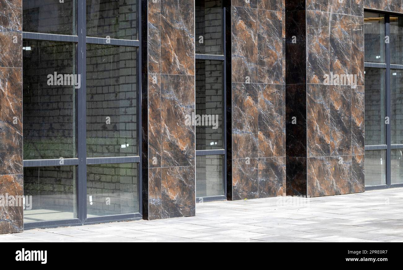 Fassade von Geschäftsräumen mit Panoramafenstern auf Straßenebene in einem neuen modernen Wohnkomplex. Gewerbliche Immobilien zur Miete in einem typischen Gebäude. Stockfoto