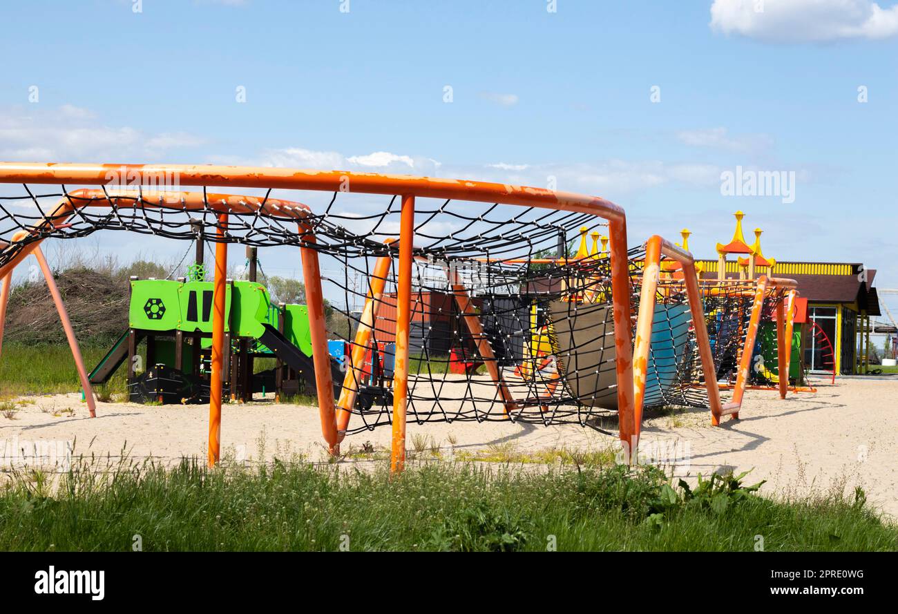 Moderner öffentlicher Spielplatz vor dem blauen Himmel. Ein farbenfroher Spiel- und Sportkomplex für Kinder ohne Menschen. Ausrüstung für Klettern und Angriff auf den Spielplatz. Stockfoto