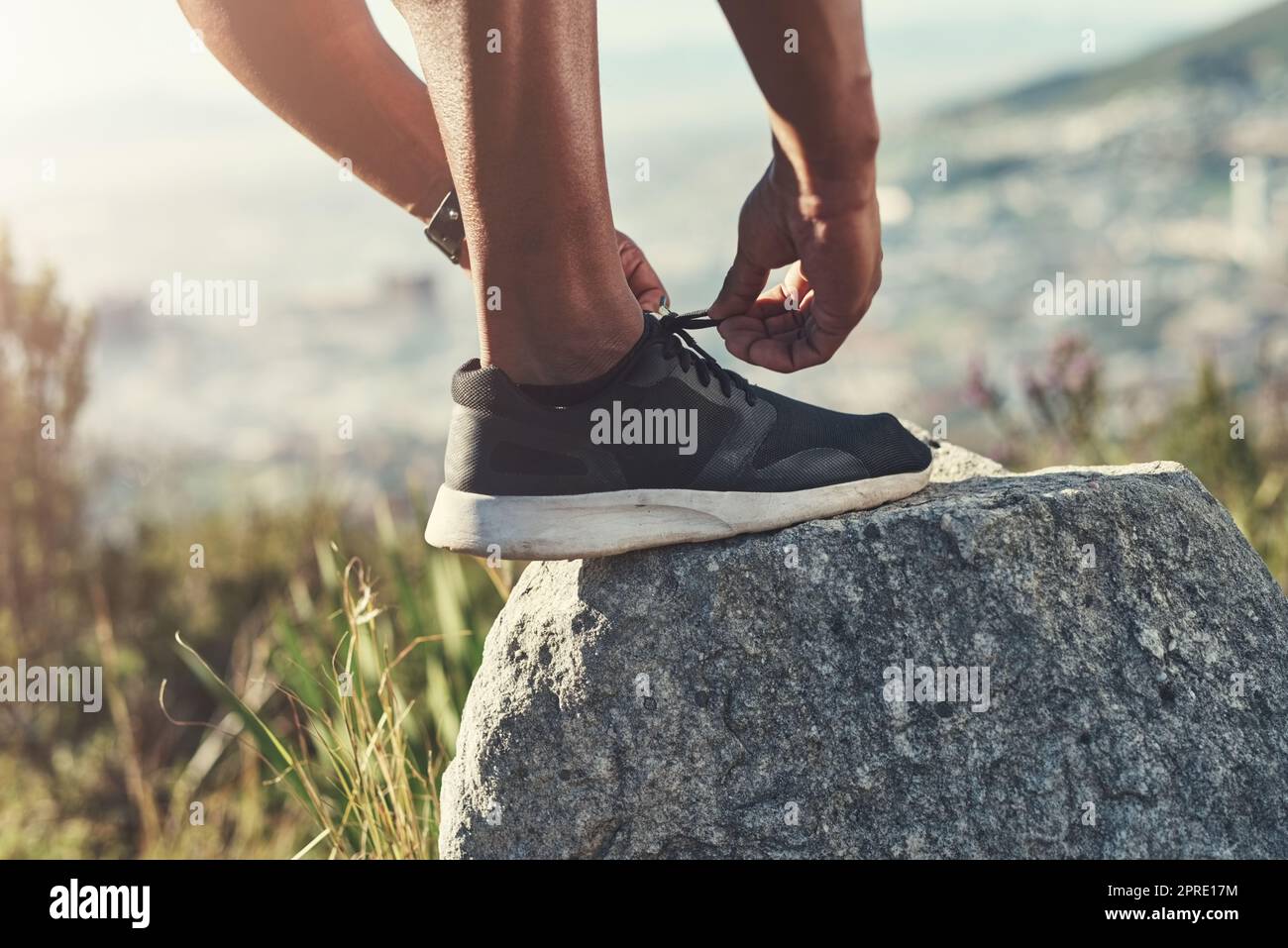 Laufen beginnt mit den richtigen Sneakers. Ein unkenntlich männlicher Läufer bindet seine Schnürsenkel im Freien. Stockfoto