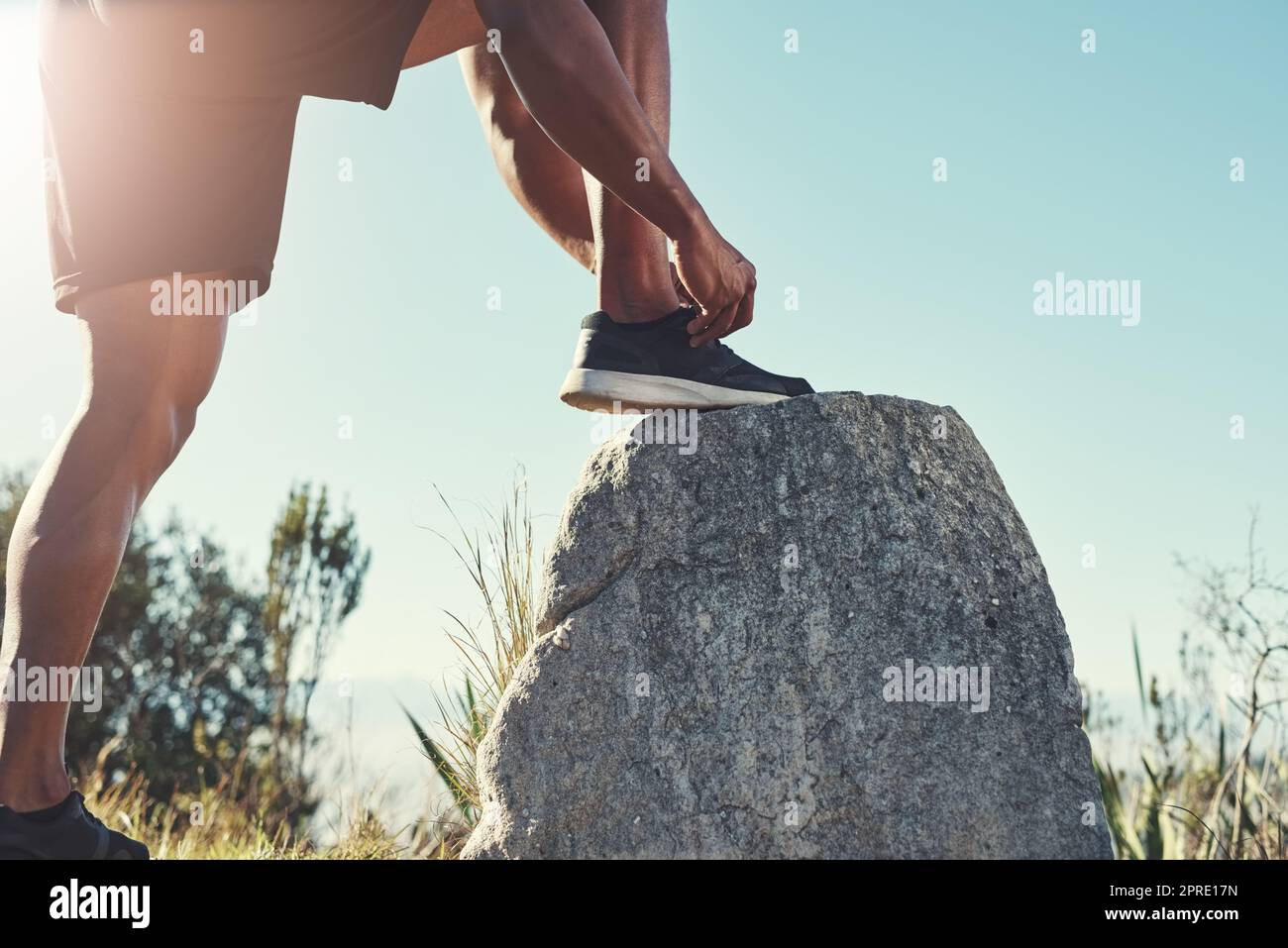 Der perfekte Ort, um meine Schnürsenkel zu binden. Ein unkenntlich männlicher Läufer bindet seine Schnürsenkel im Freien. Stockfoto