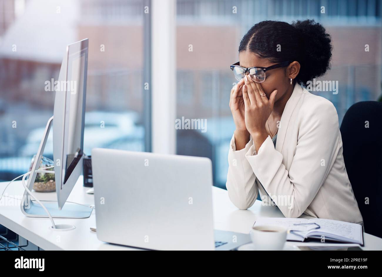 Von ehrgeizig bis ausgebrannt. Eine junge Geschäftsfrau, die gestresst an ihrem Schreibtisch in einem modernen Büro aussieht. Stockfoto