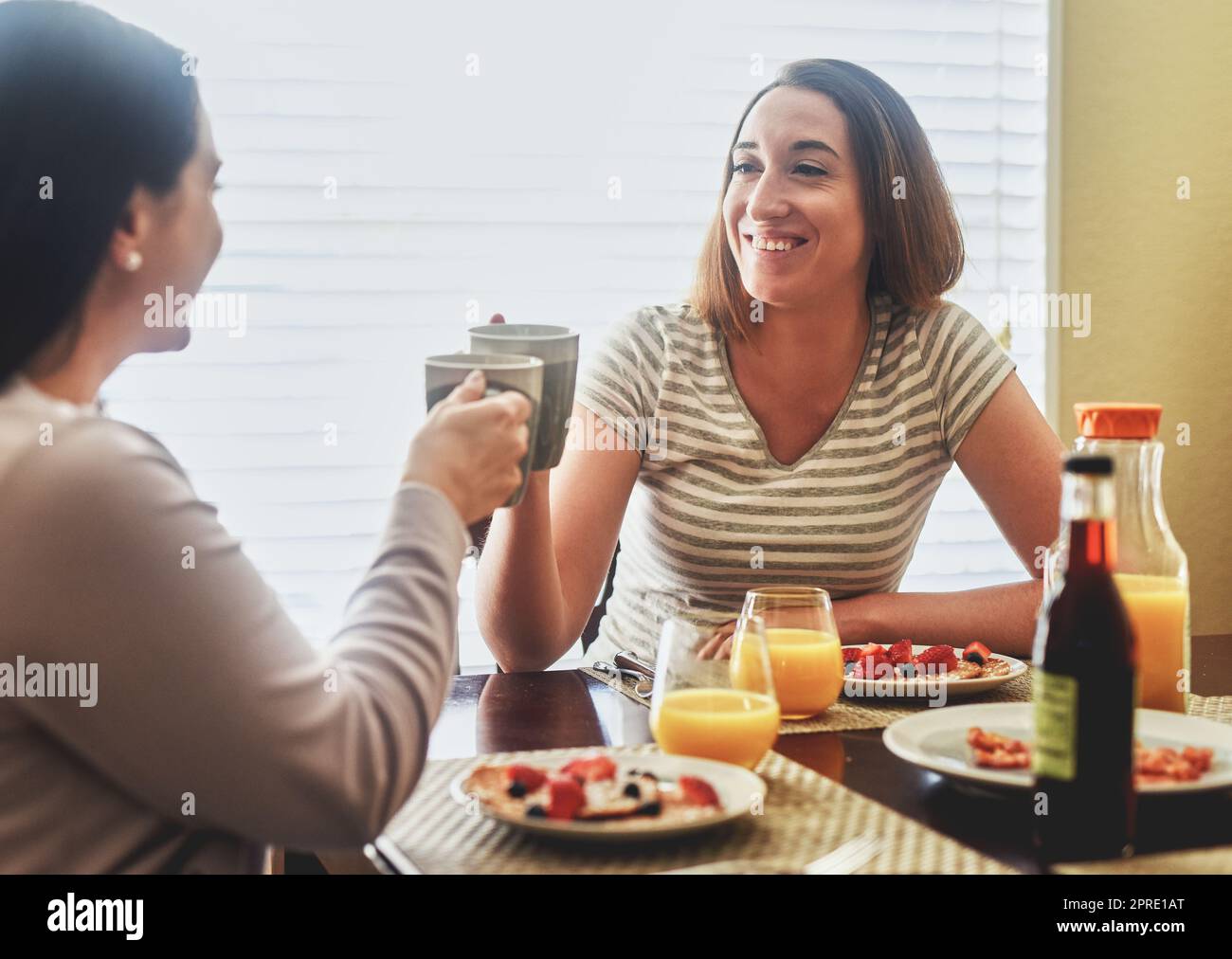 Jubel zum Beginn eines schönen Tages. Zwei junge Frauen frühstücken morgens zu Hause. Stockfoto