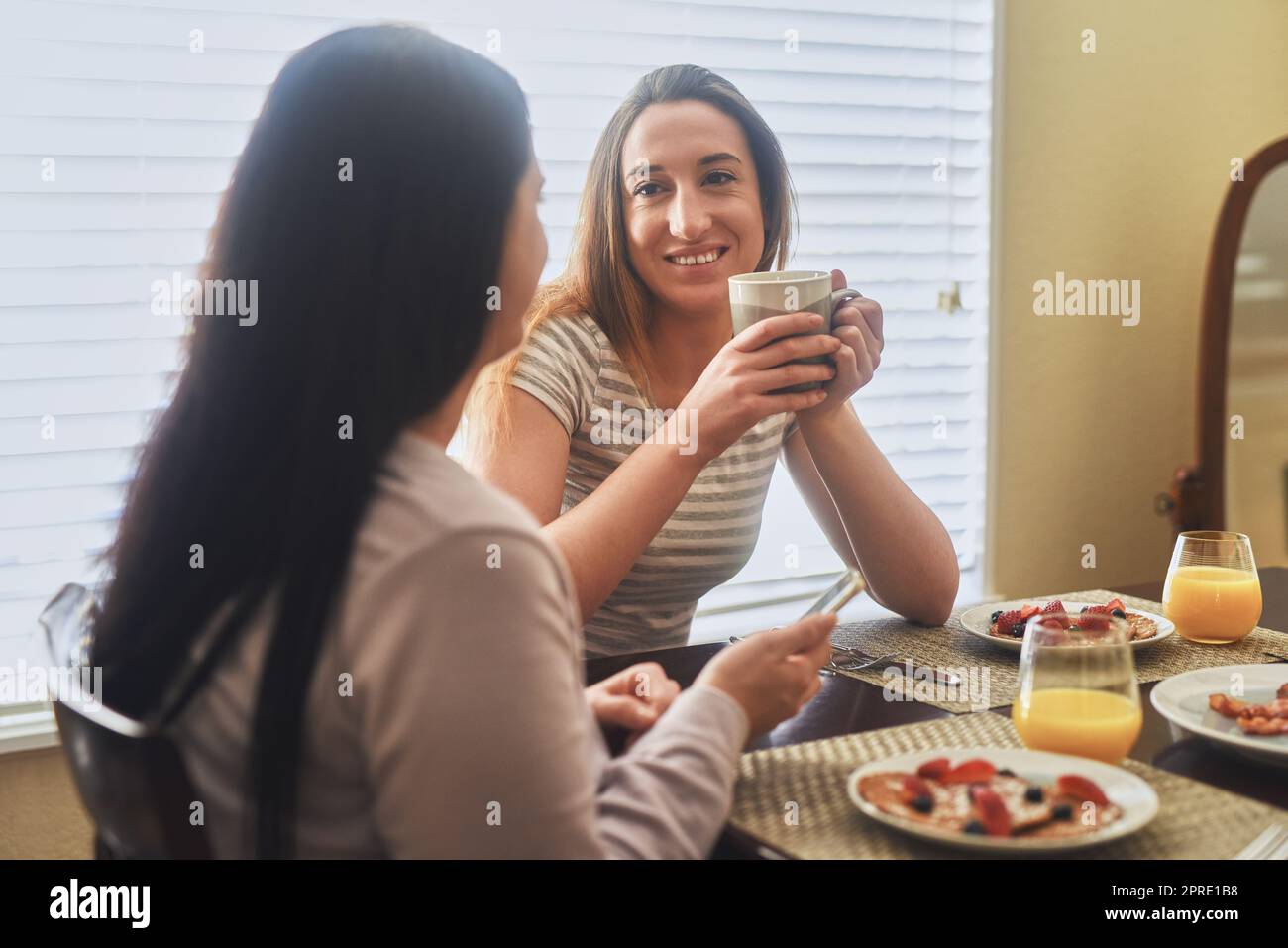 Unsere morgendlichen Gespräche sind die besten. Zwei junge Frauen, die morgens zu Hause frühstücken. Stockfoto
